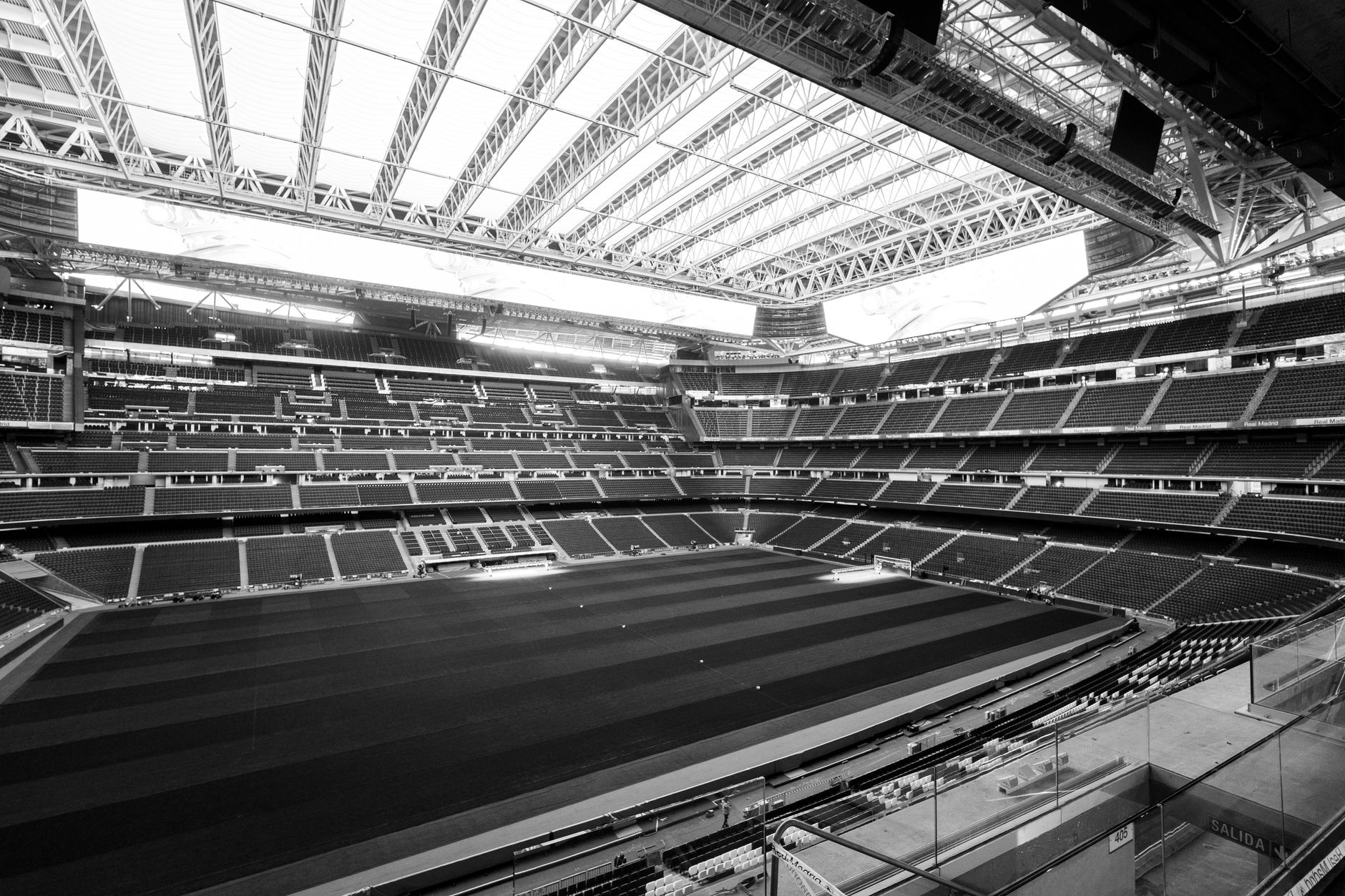wide view of a large stadium interior before an event, empty seats and field visible under bright artificial lighting, no people in foreground