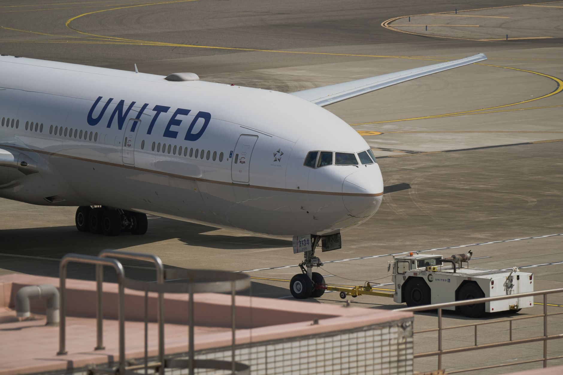 a large remotely piloted aircraft parked on a sun-bleached desert flight line at a Nevada air base, maintenance equipment visible nearby, wide environmental shot with heat shimmer on the tarmac