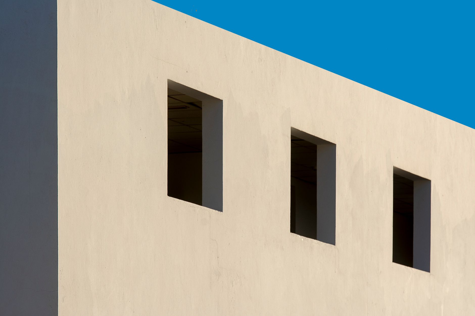 exterior view of newly constructed modular military barracks buildings at a desert Army installation, low-profile rectangular structures with smooth concrete walls under a clear sky