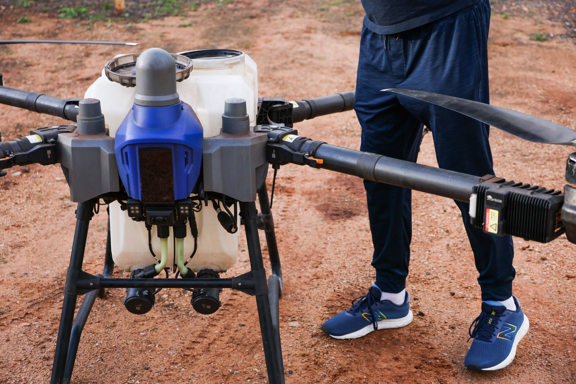 a large unmanned aerial vehicle in a desert flight test facility, viewed from the side on a concrete tarmac with maintenance equipment nearby