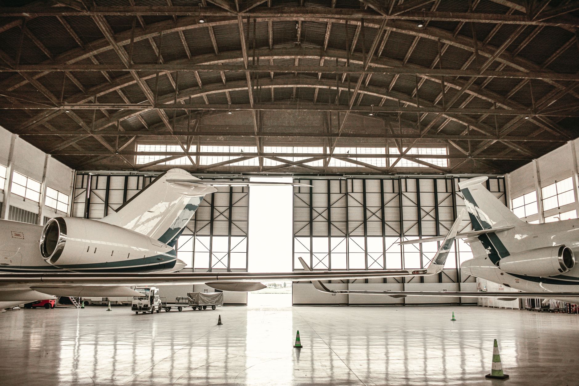 aerial view of a large aerospace manufacturing facility with wide production hangars and parked transport vehicles on the tarmac