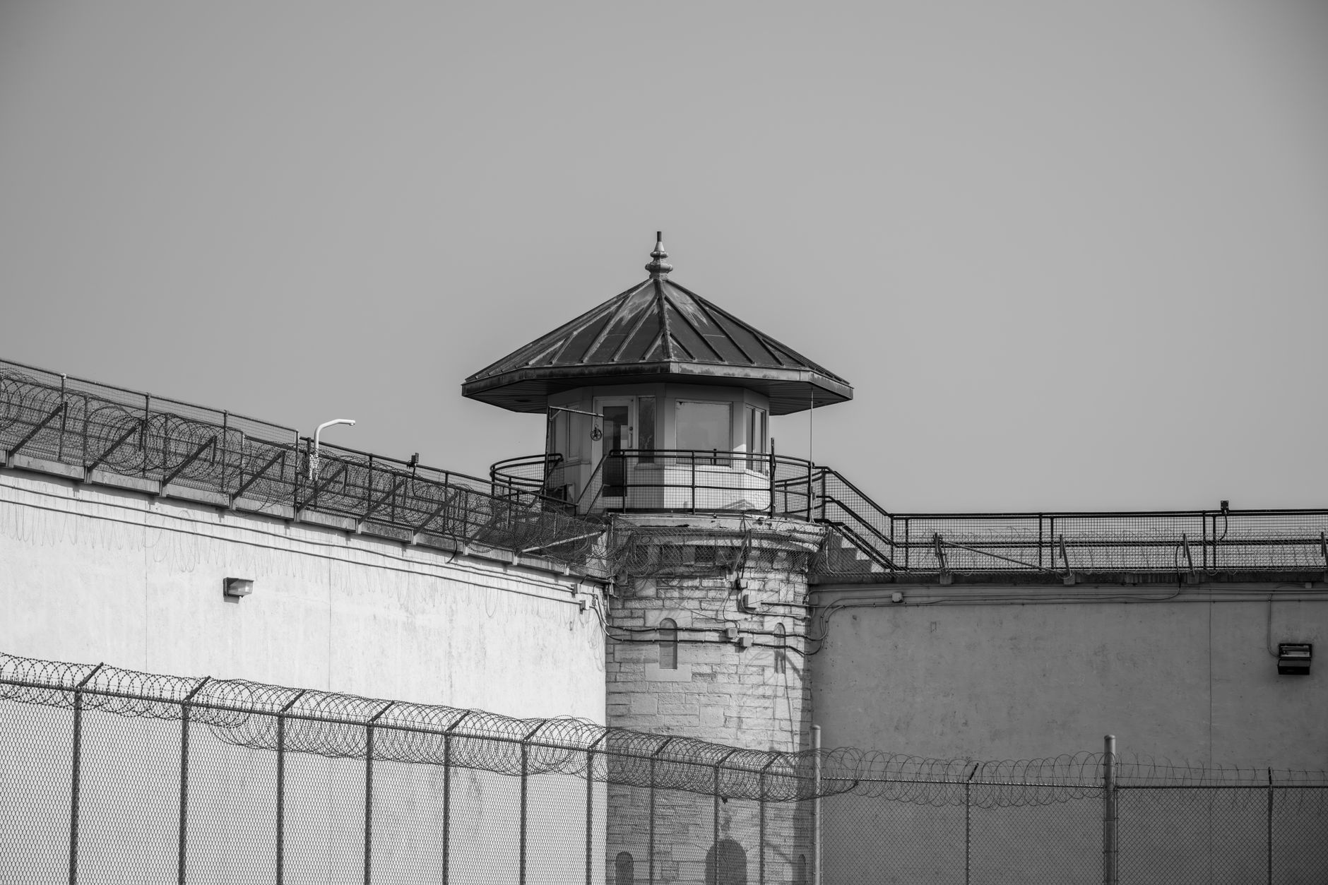 aerial view of a secure defense manufacturing facility exterior, surrounded by perimeter fencing, no personnel visible
