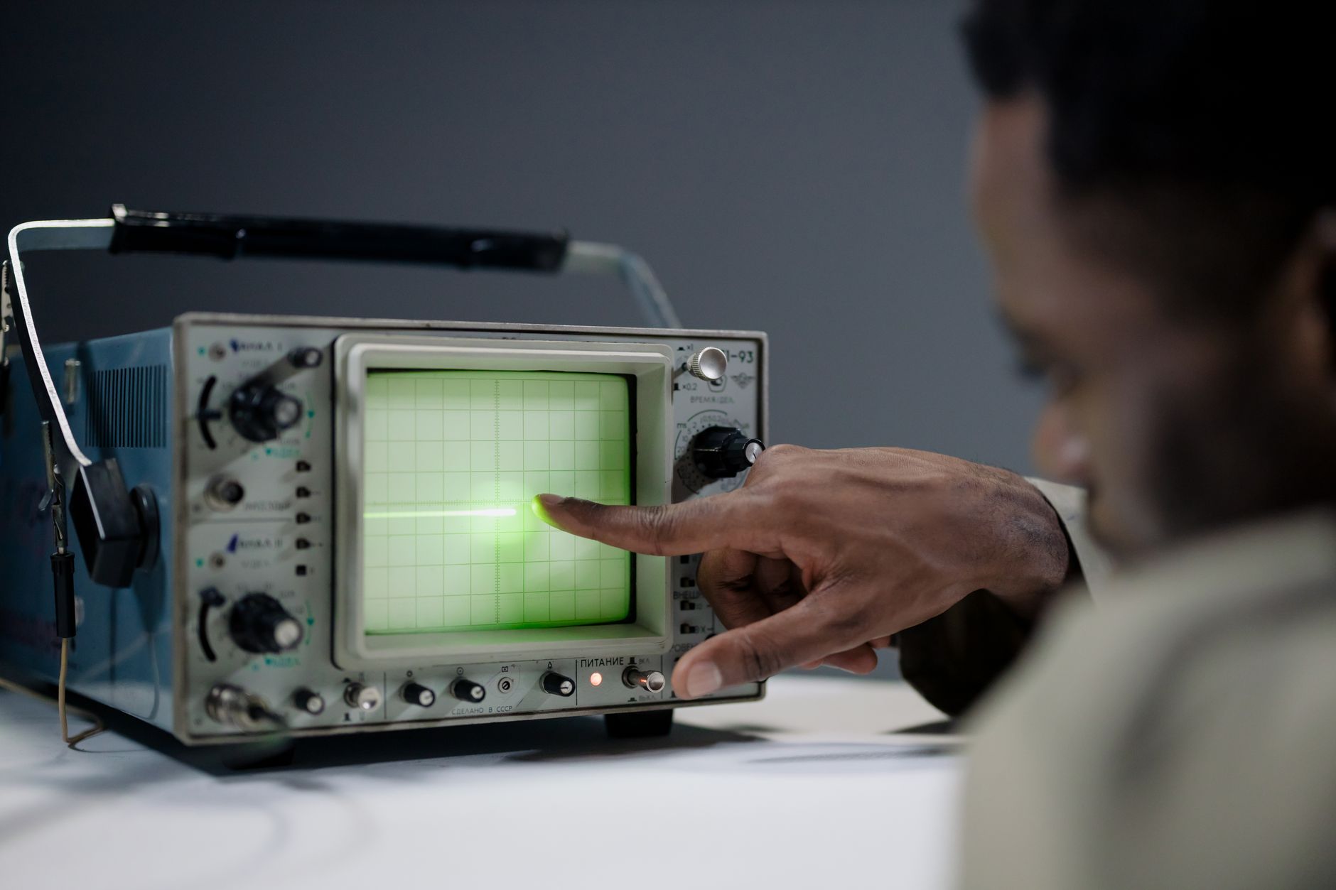 a research laboratory interior with electronic signal processing equipment, oscilloscope screens displaying waveform data, and antenna components on a workbench