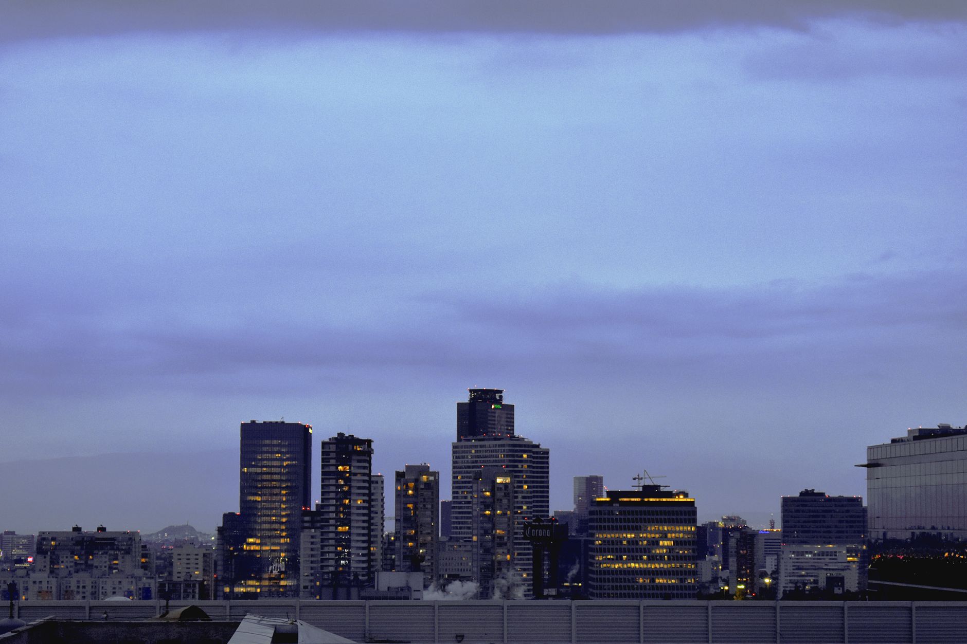 a large financial district skyline at dusk with office towers lit from within, wide environmental shot with no visible faces