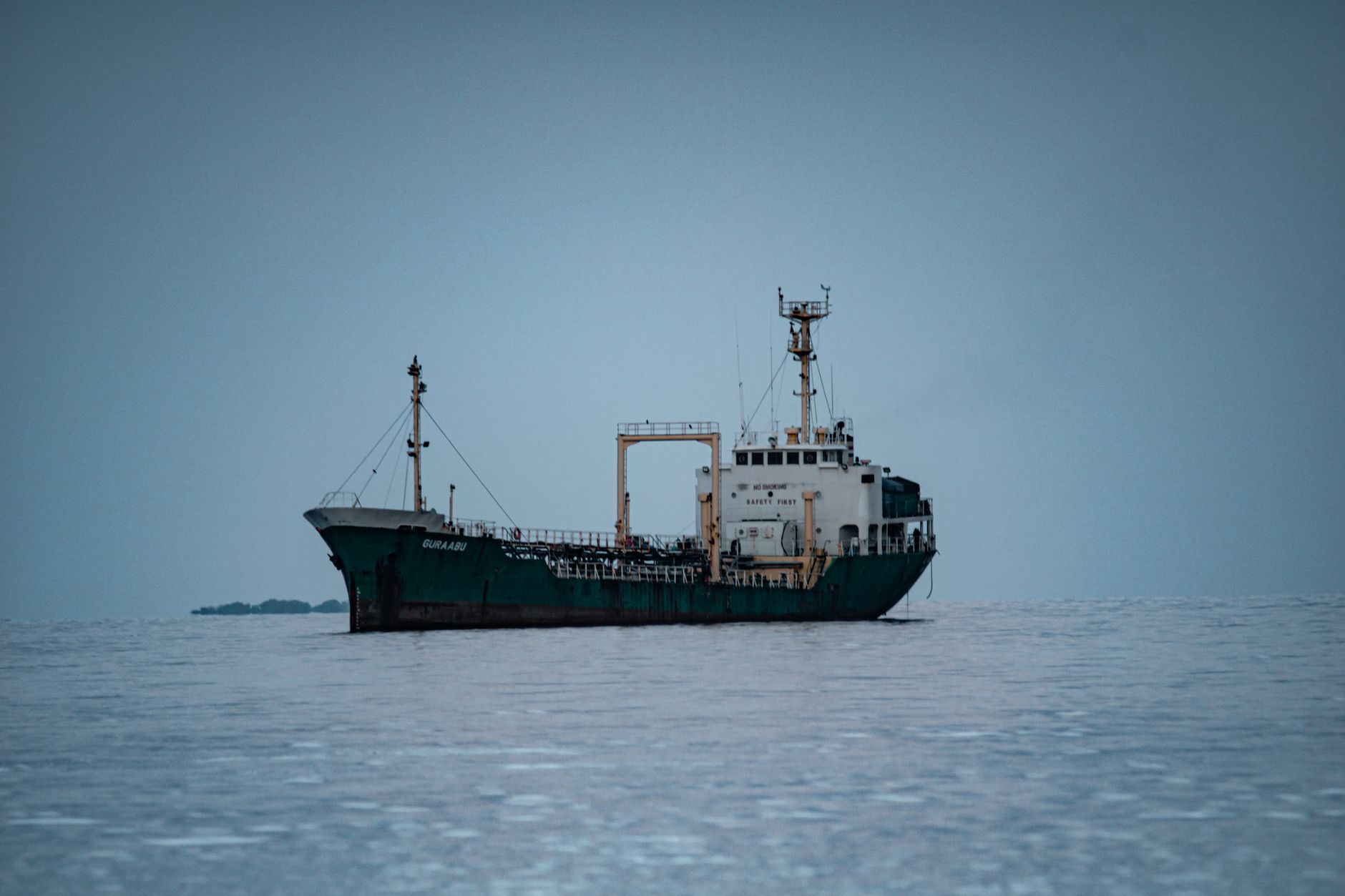 a naval research vessel at anchor in open water, with hull-mounted sonar arrays visible along the waterline
