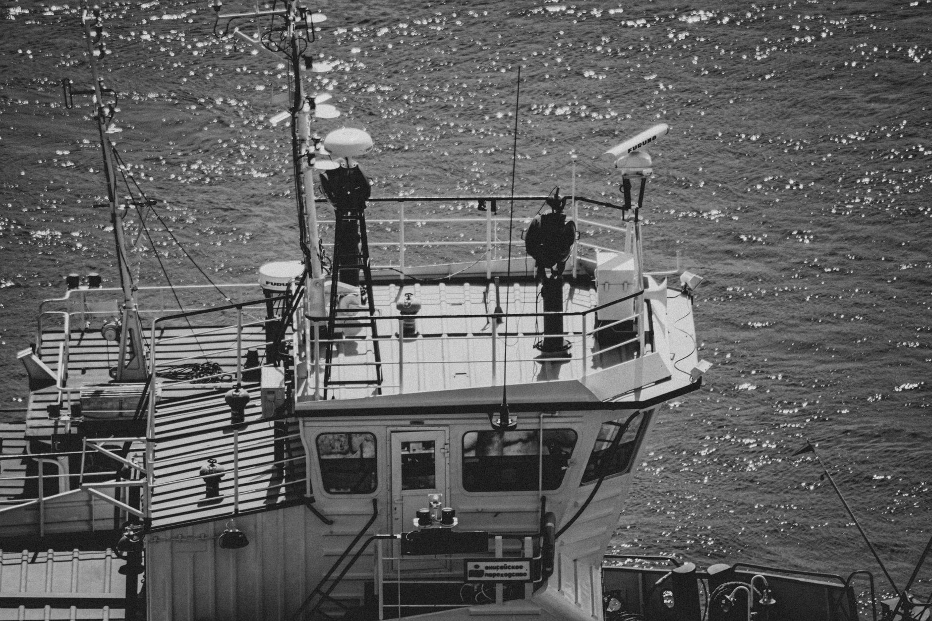 an underwater autonomous vehicle being recovered over the side of a small research boat, with crew standing nearby on deck