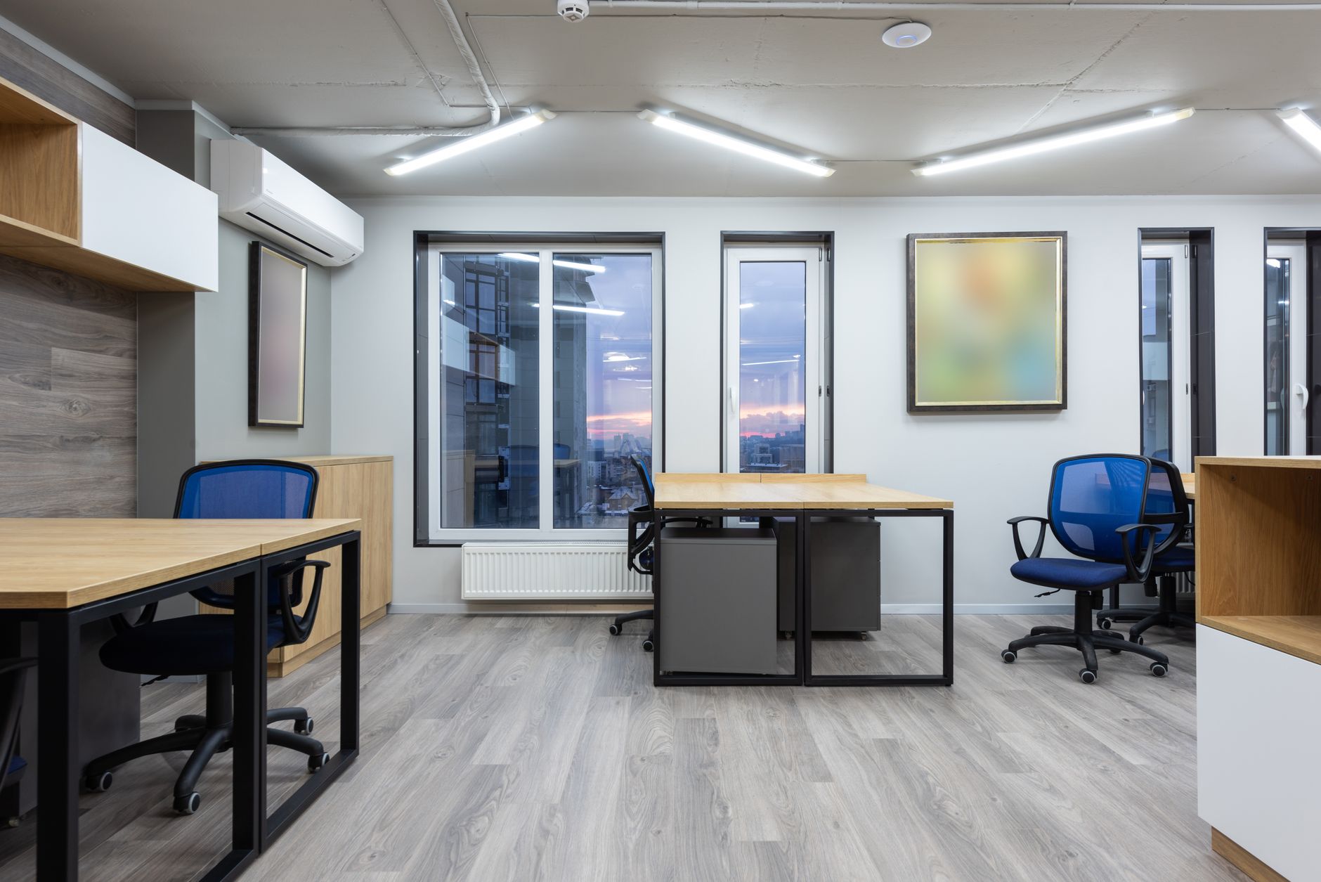 an empty commercial office floor in a large urban high-rise, rows of vacant workstations visible through floor-to-ceiling windows overlooking a city street below
