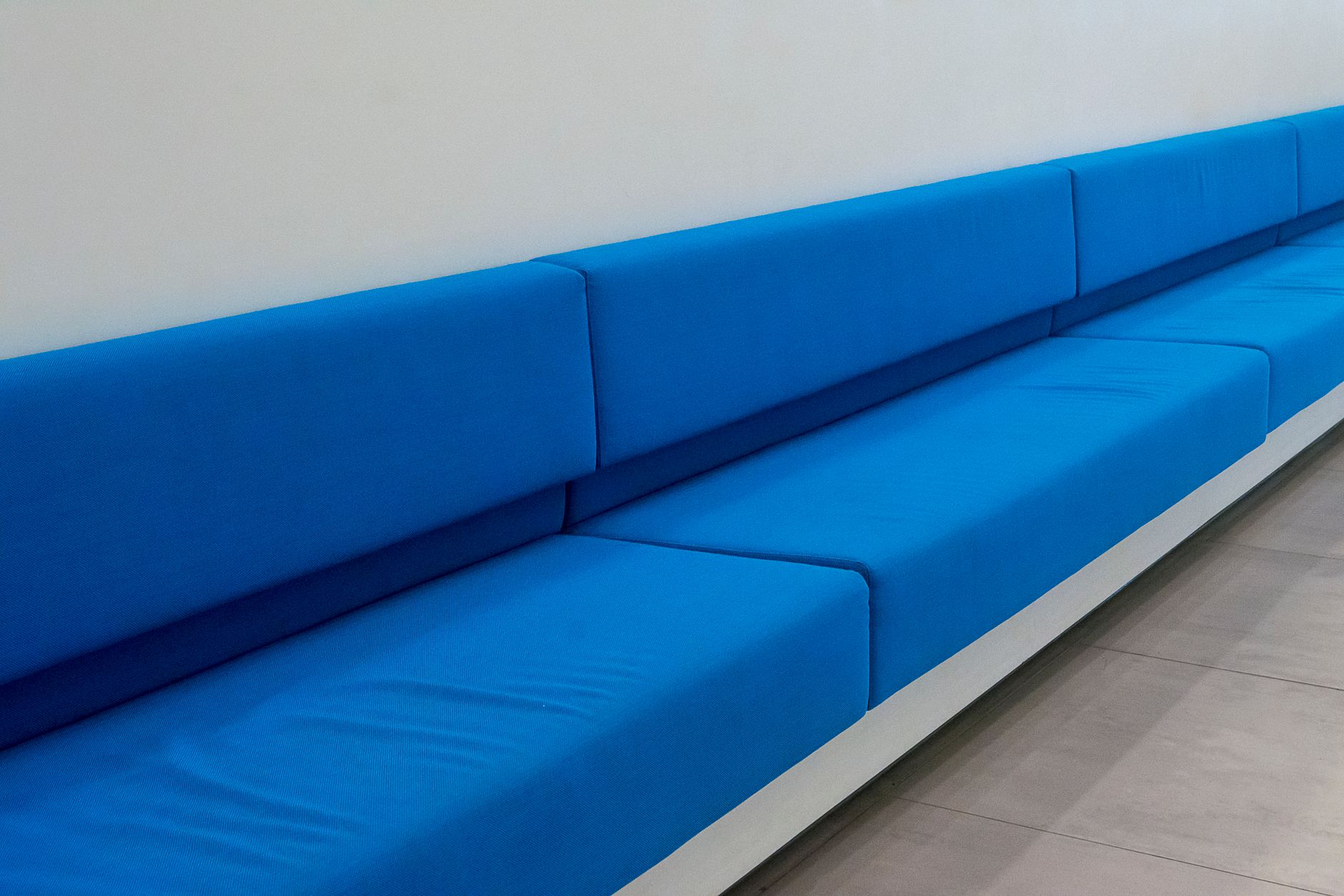 an empty government office waiting room with rows of chairs and information pamphlets on a wall-mounted rack, institutional lighting, no people visible