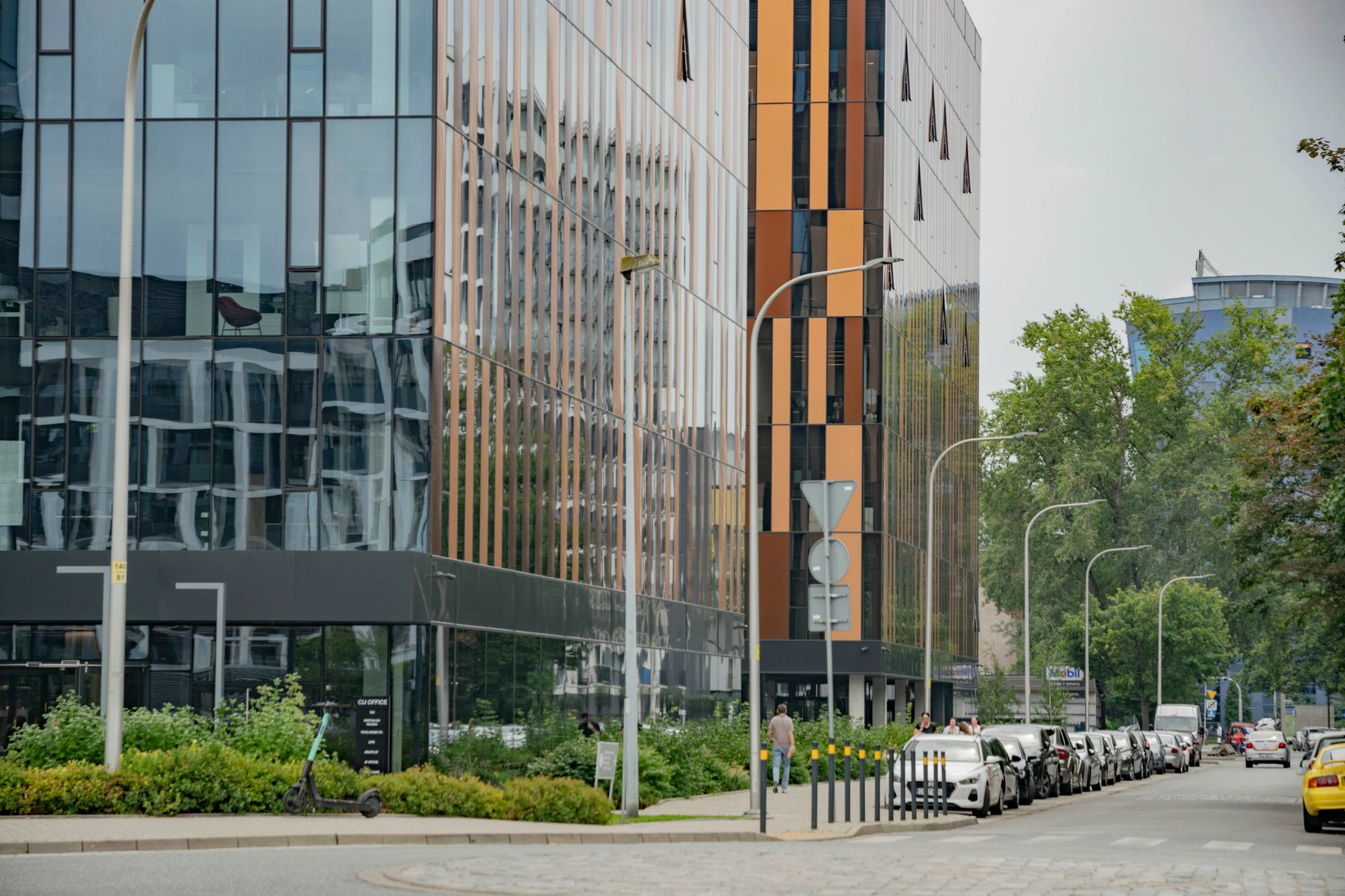 a modern glass-facade technology office building in a dense urban business district, exterior shot showing multiple floors with open-plan workspaces visible through windows