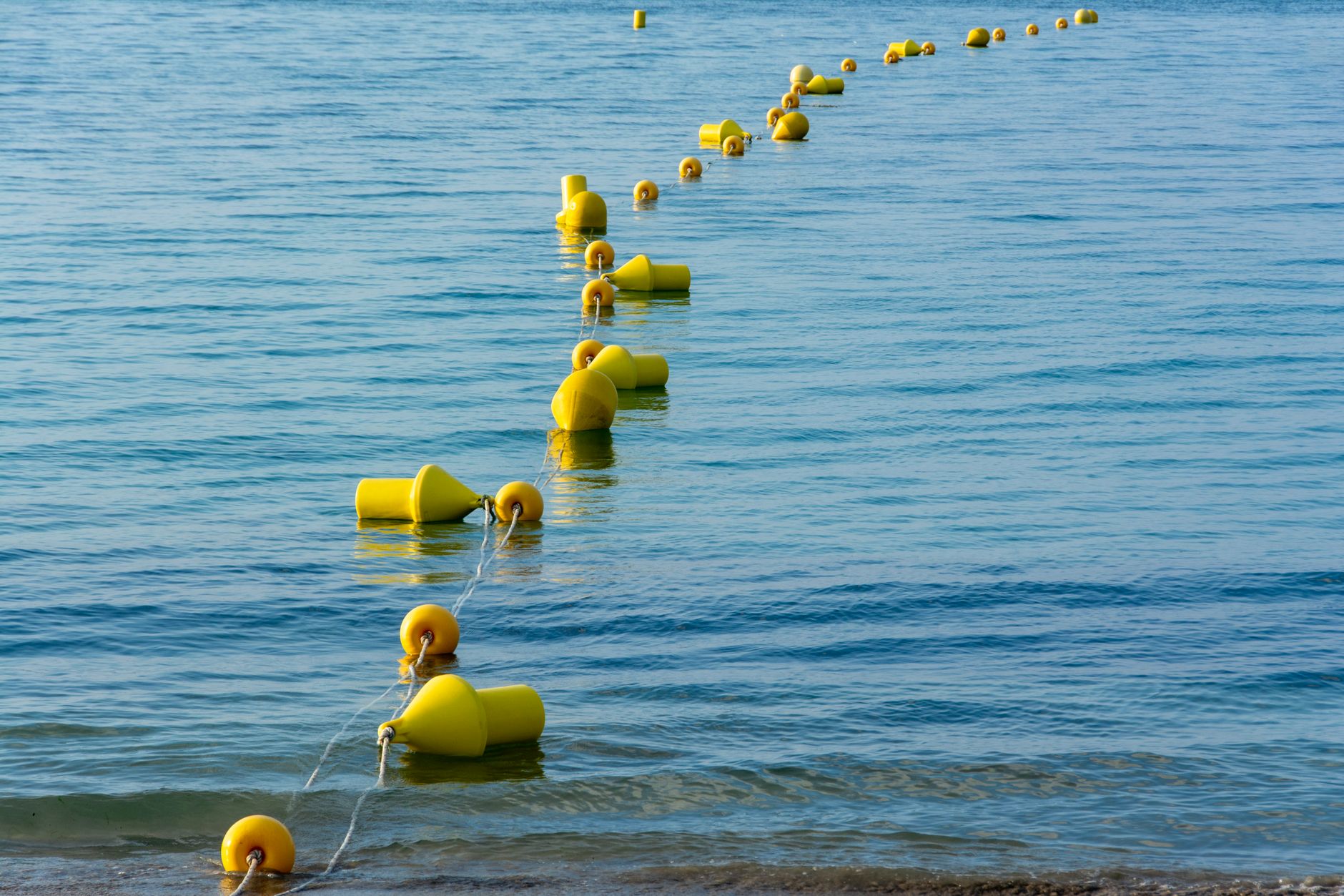an autonomous ocean buoy system floating on open water, with solar panels and sensor arrays visible on its superstructure, anchored in a calm sea