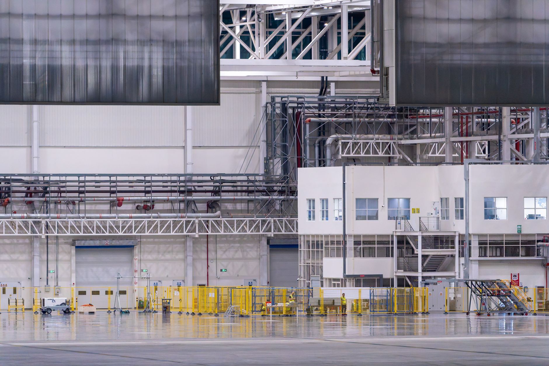 rows of assembled remote weapon station units inside a large industrial production facility, with workbenches and overhead lighting visible in the background