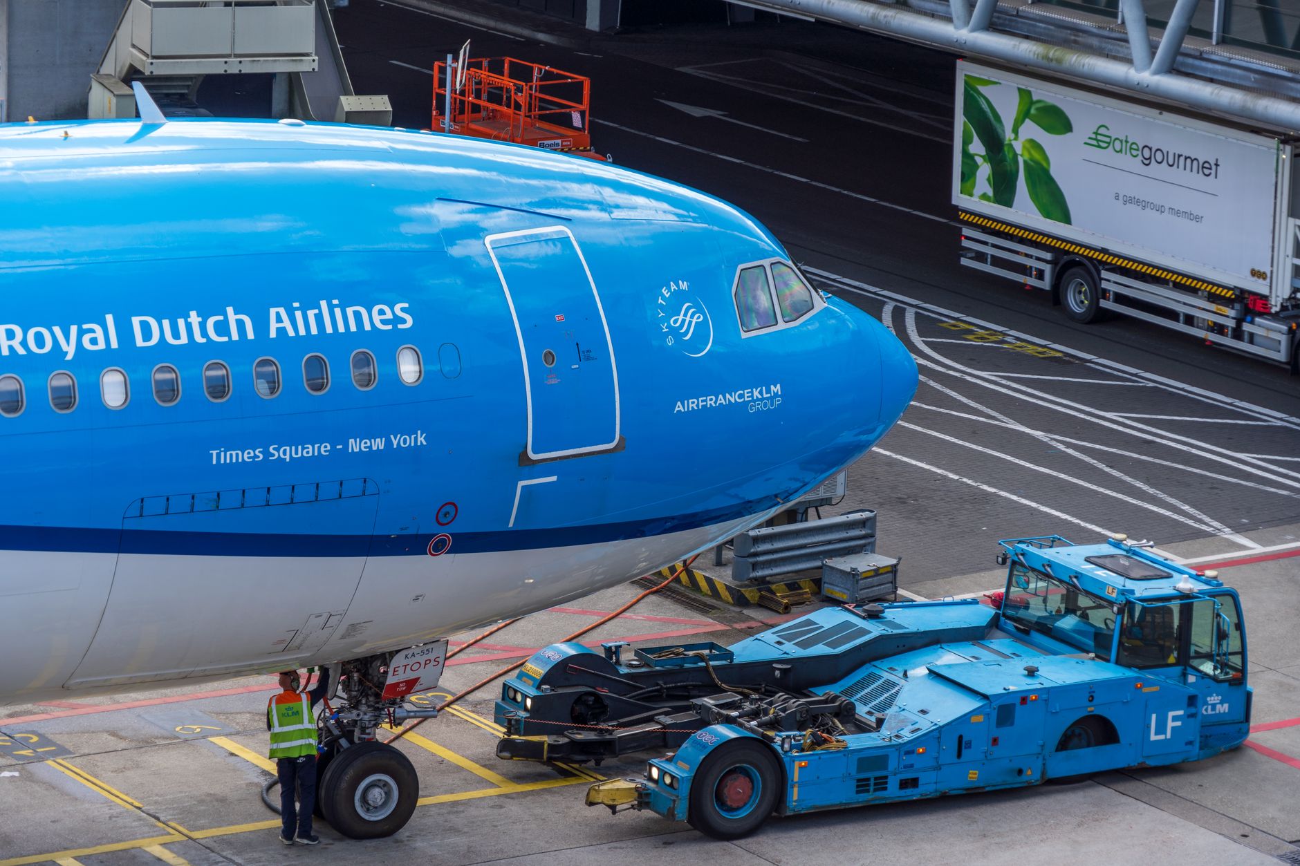 military cargo aircraft being loaded with equipment pallets at a large air base, forklifts and logistics support vehicles positioned around the aircraft on a wide concrete apron
