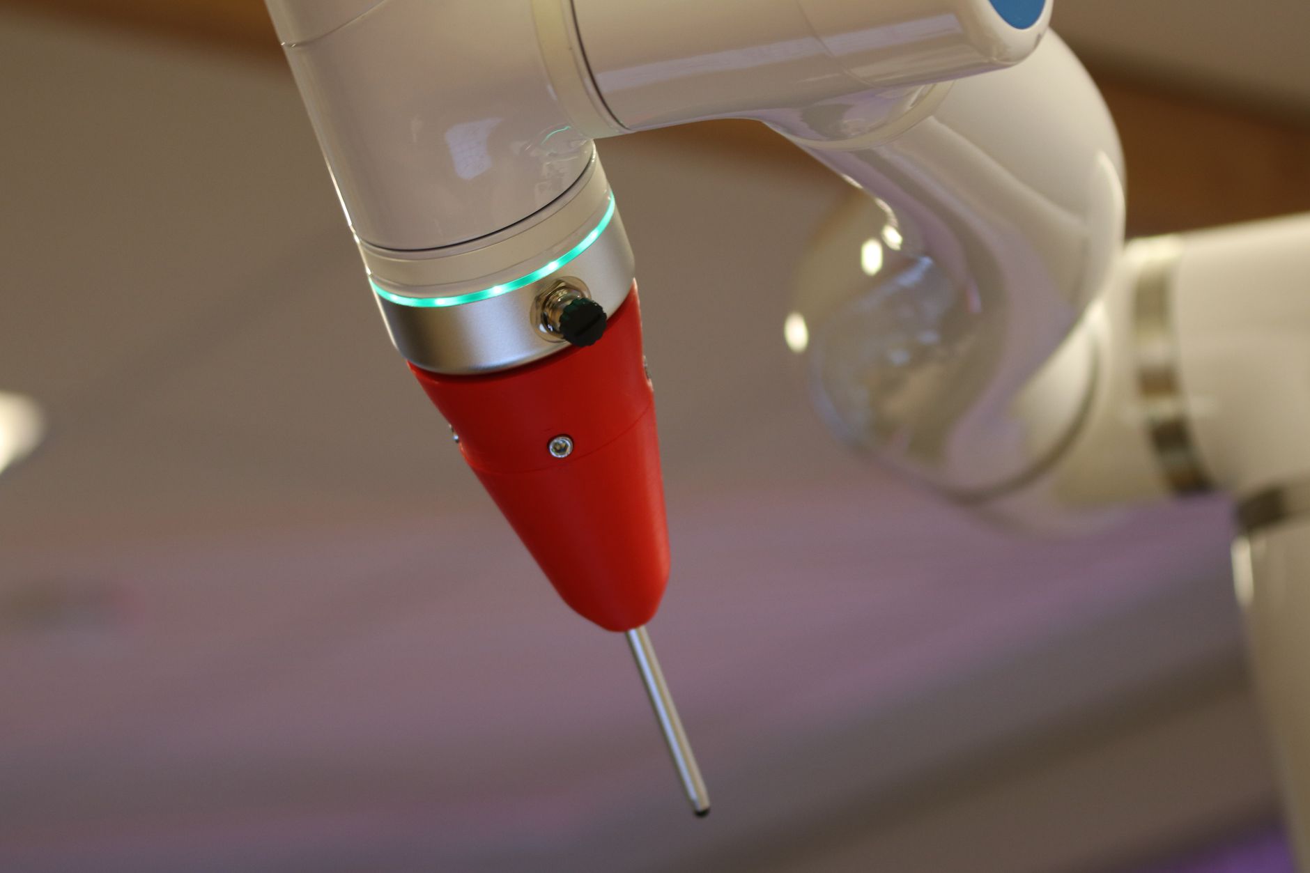 close-up of a flexible robotic arm extended into a cylindrical mechanical enclosure in an aerospace manufacturing environment, tools visible at the arm's tip