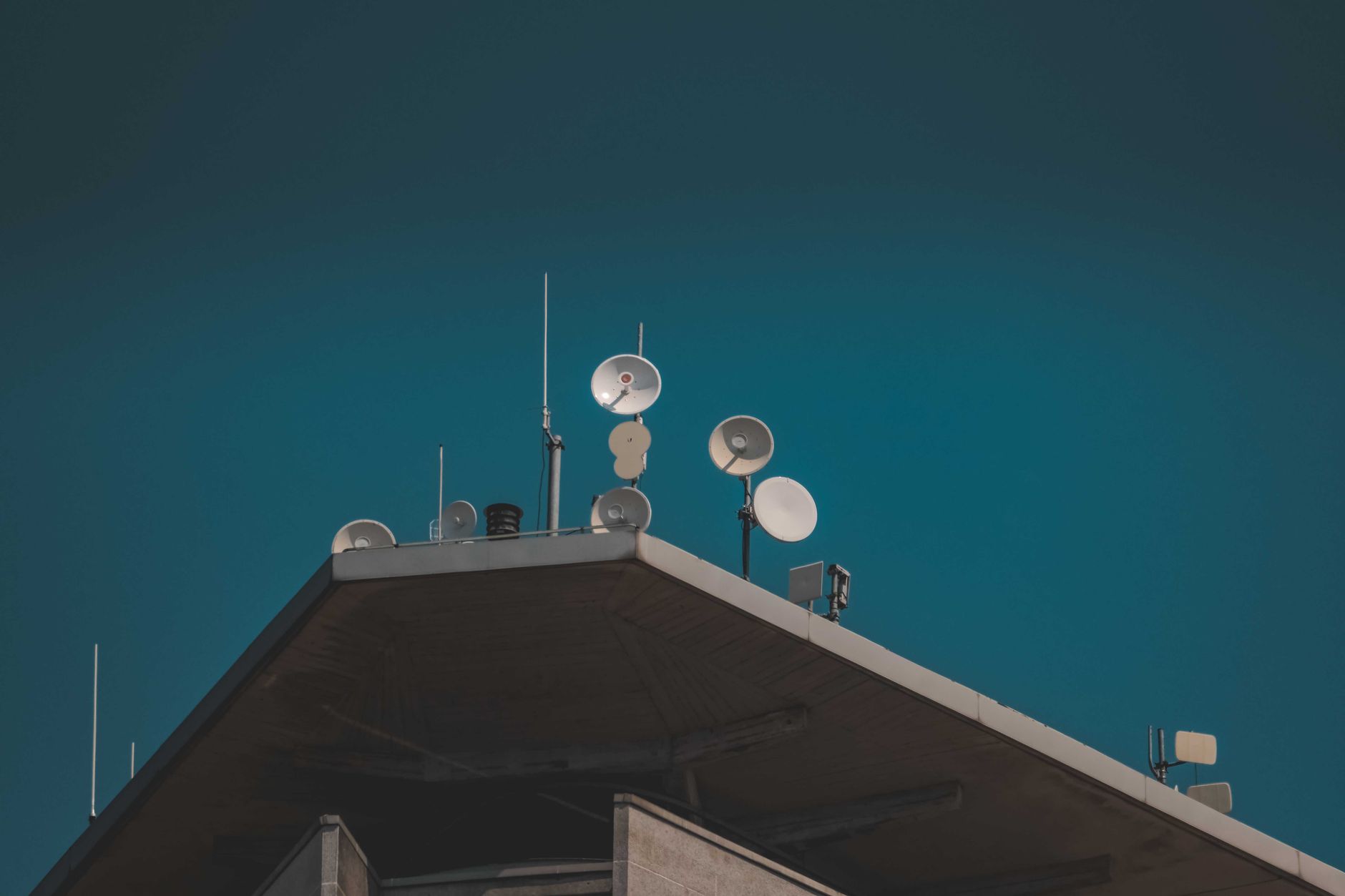 exterior of a modern research campus with glass facades and satellite dishes, set against an overcast sky