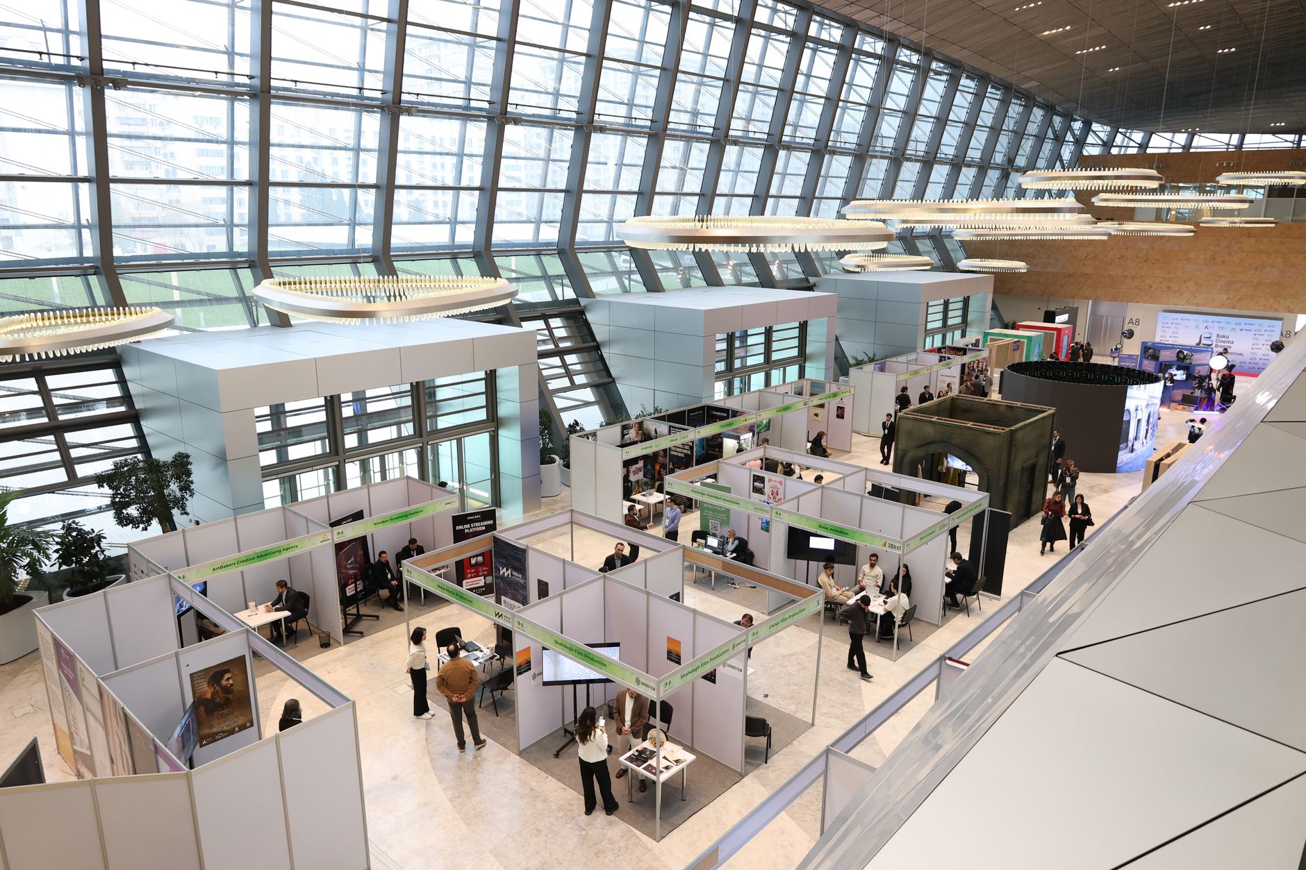 a large government conference facility interior with exhibition booths displaying small unmanned systems and communications hardware, wide shot with sparse attendees in background