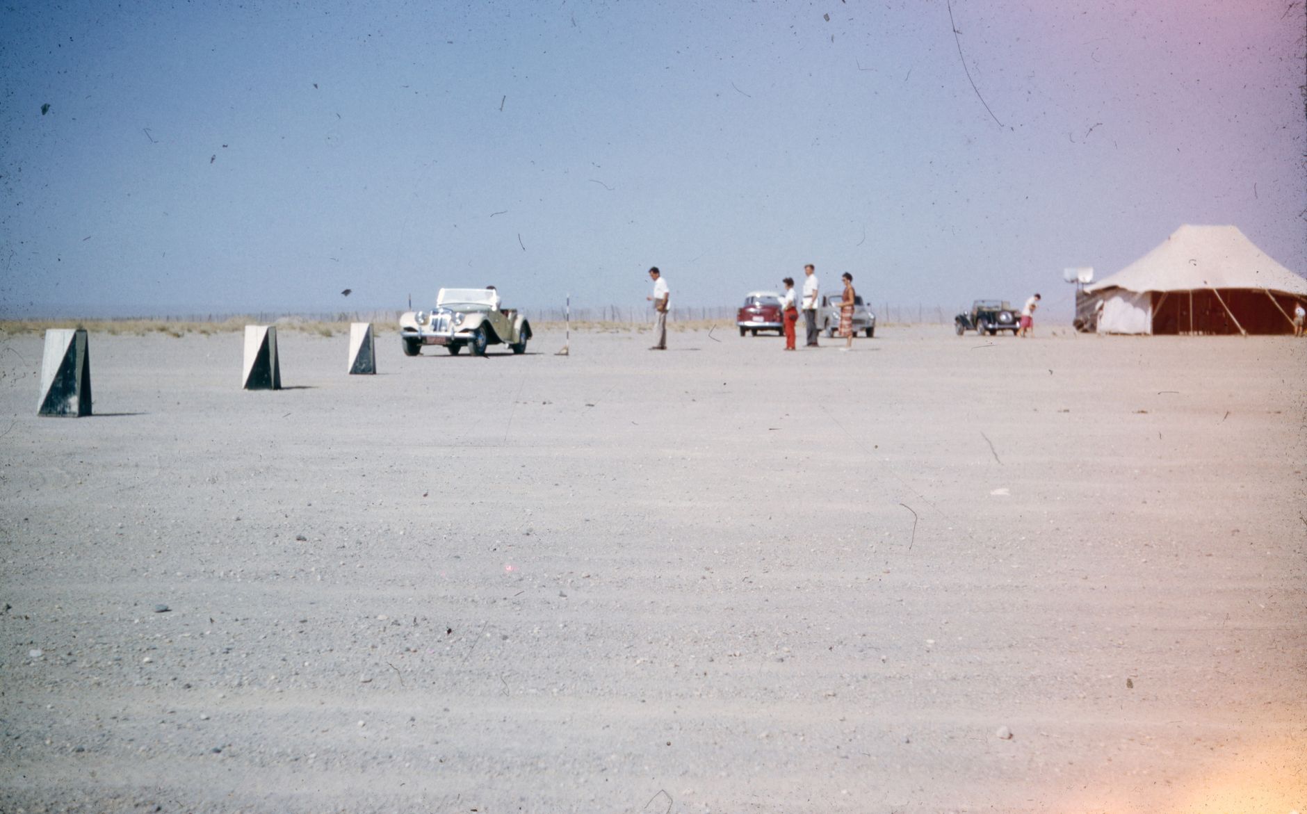a secure government testing range with small autonomous ground vehicles and portable communications equipment arranged for evaluation, wide environmental shot with no personnel in foreground
