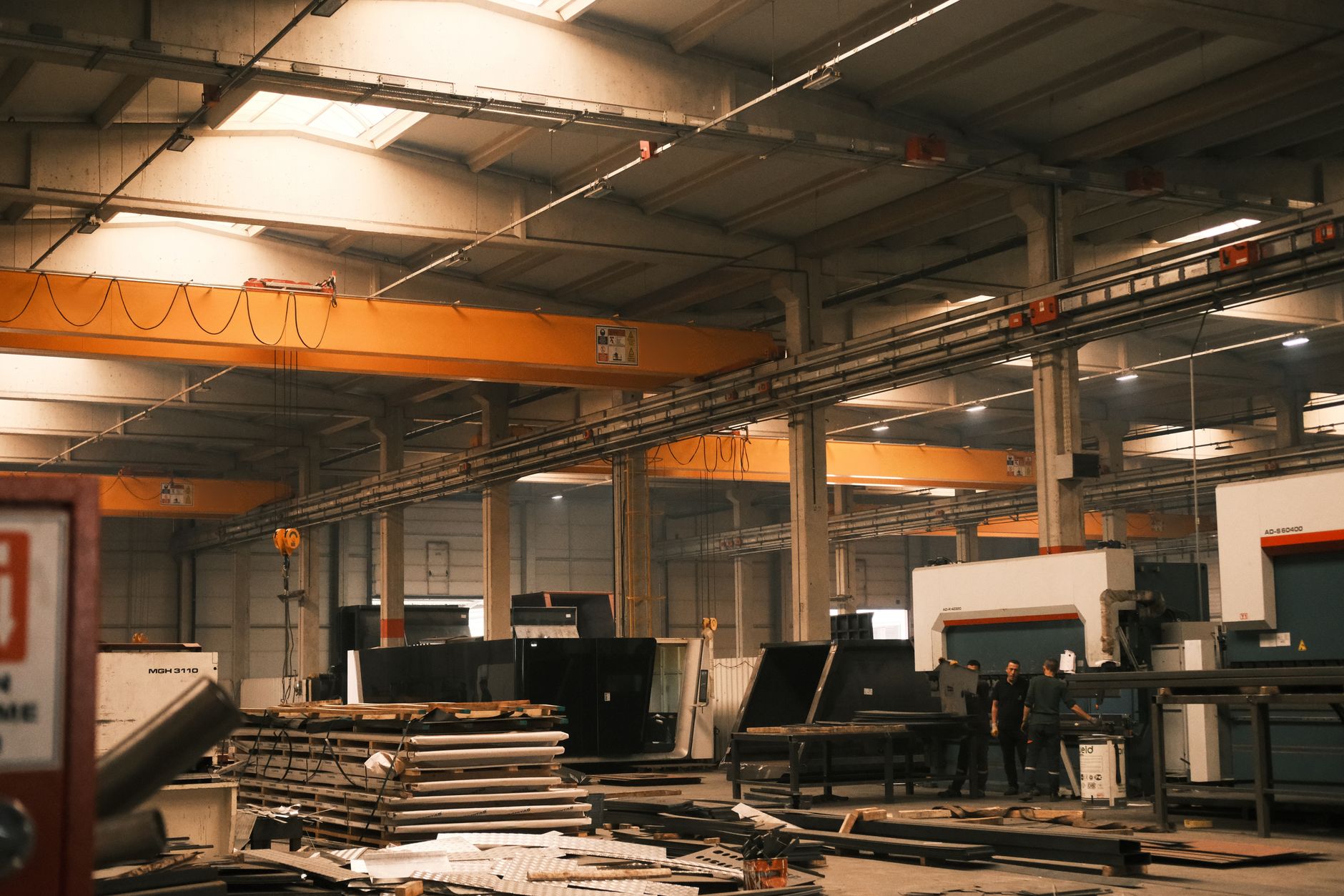 the interior of a rocket integration facility with a large payload fairing suspended by overhead crane equipment above a clean-room floor