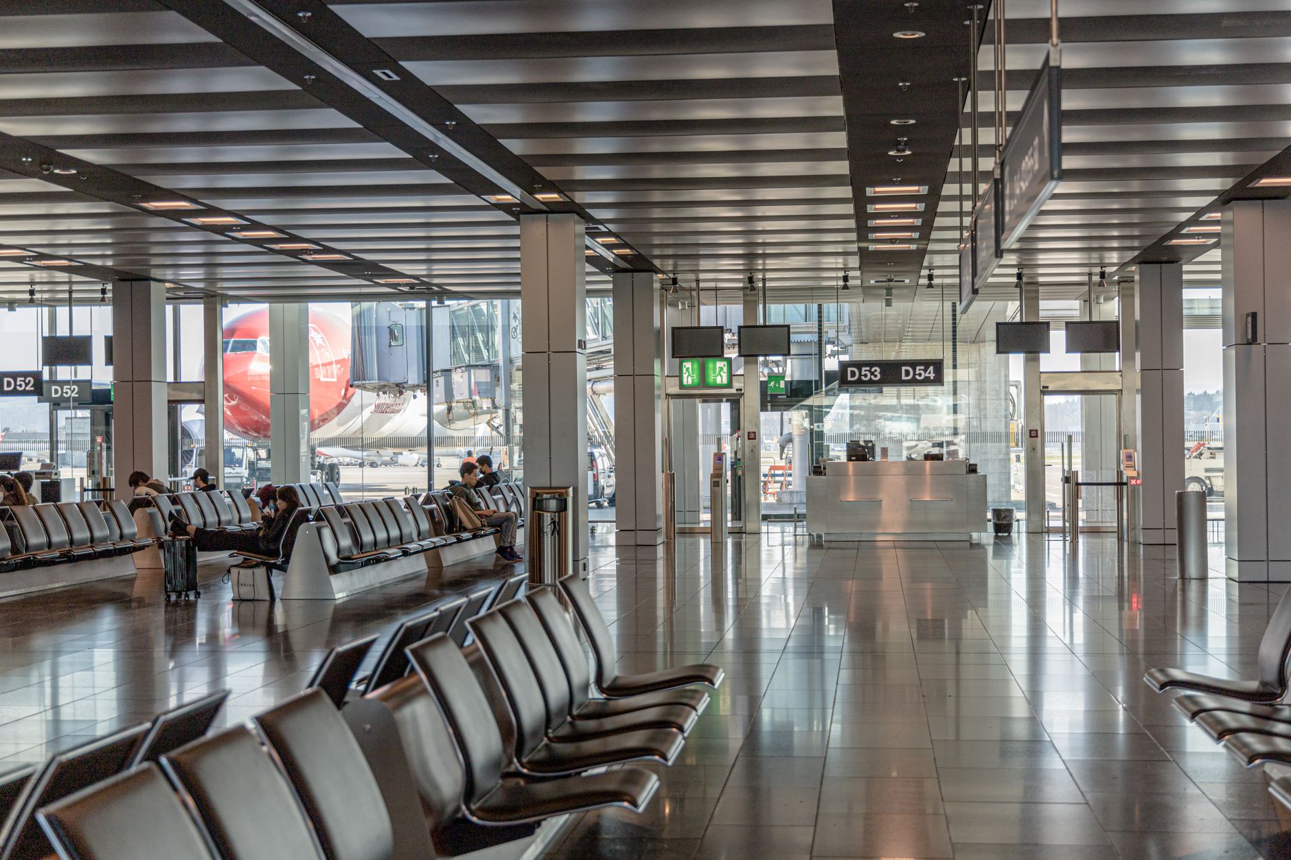 wide-angle view of an international airport terminal departure board displaying multiple canceled and delayed flights, empty gate seating in the foreground