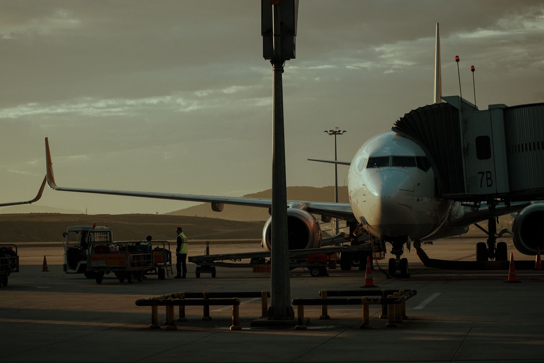 a commercial passenger jet parked at a remote stand on an airport tarmac at dusk, ground support equipment idle nearby