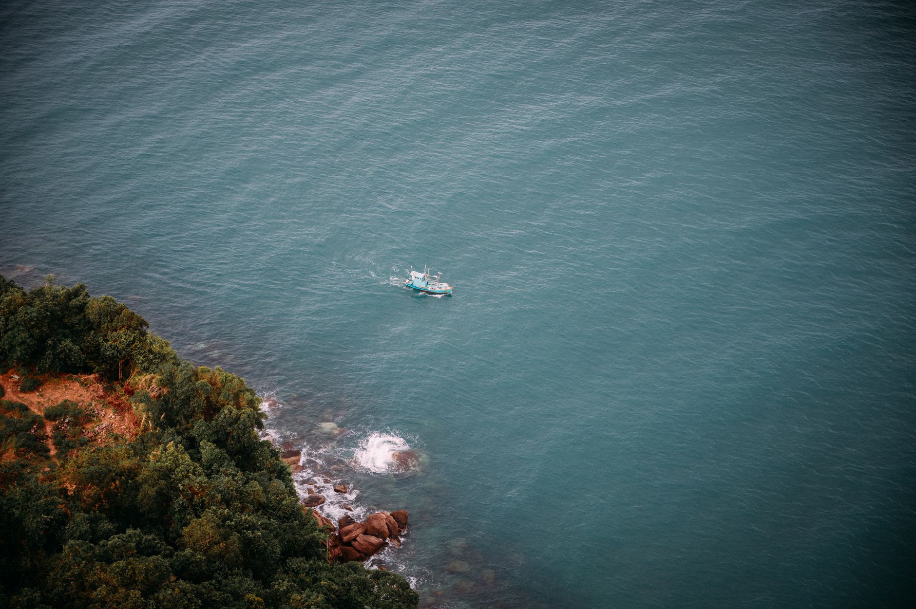 a large crude oil tanker anchored in a narrow strait, viewed from an aerial perspective showing rocky coastline on either side