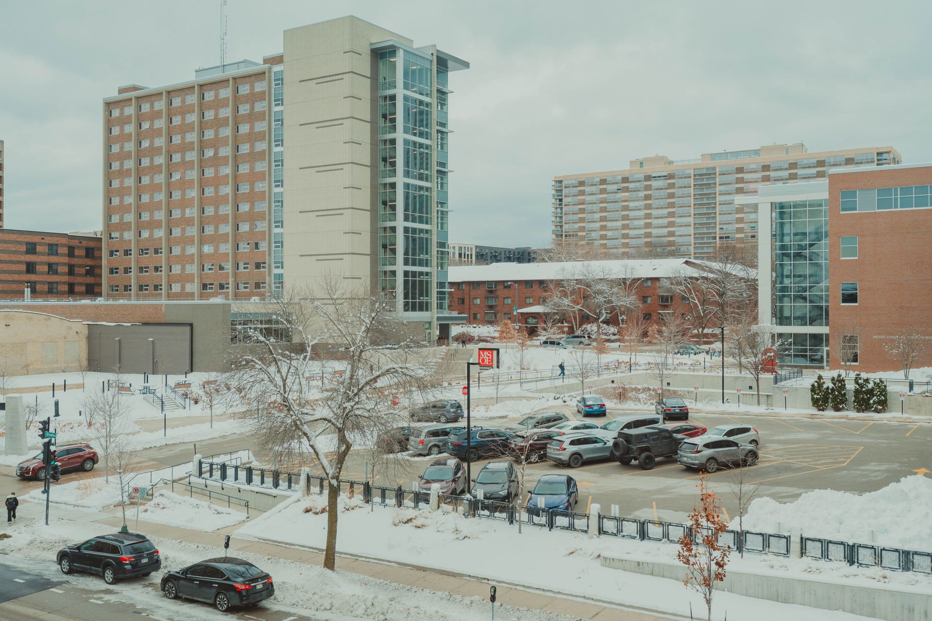 exterior view of a Department of Veterans Affairs medical center building with a parking lot and American flag visible in the background, taken during daytime