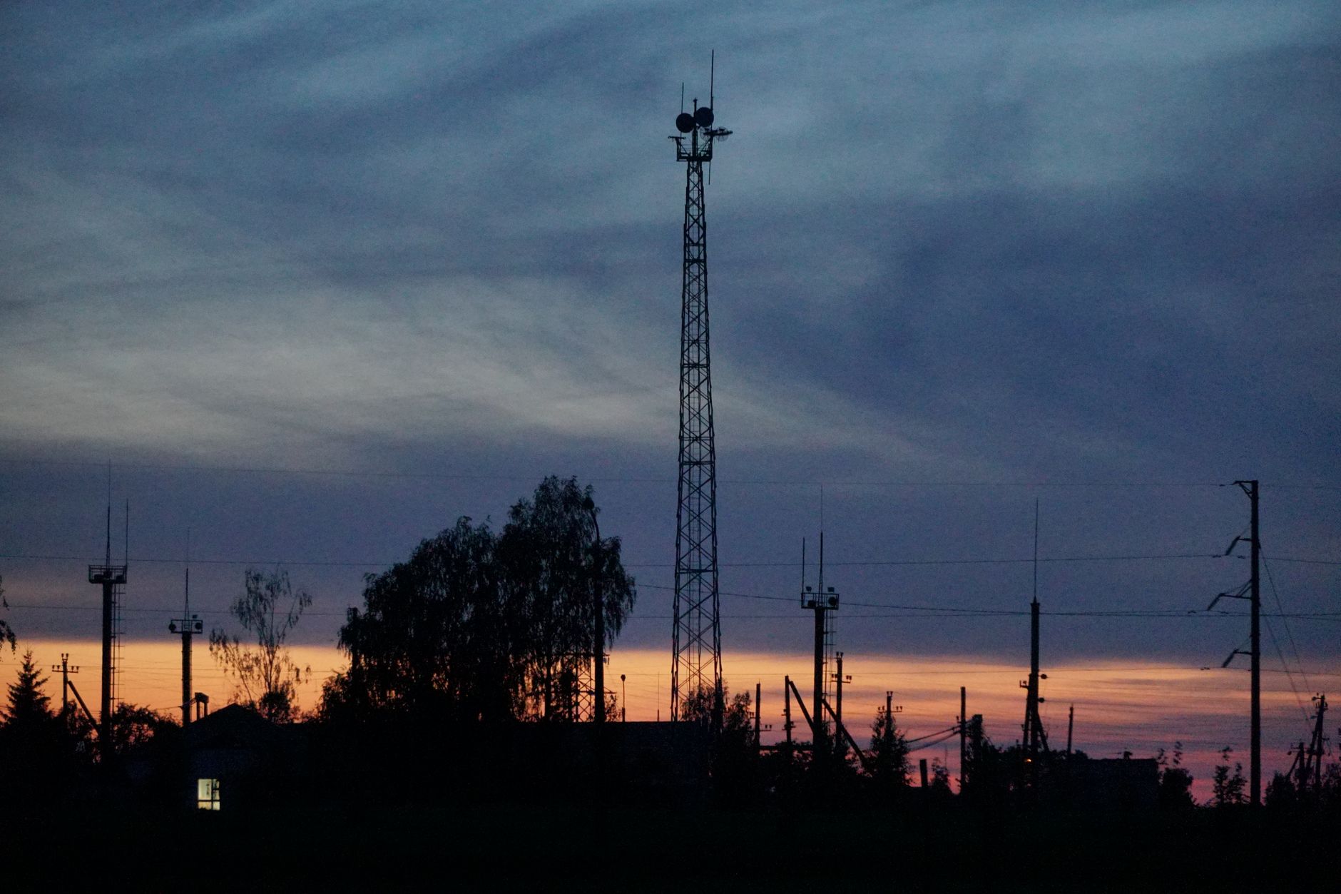 a U.S. Air Force ground communications antenna array on a flight line at dusk, satellite dishes and antenna masts visible against an open sky