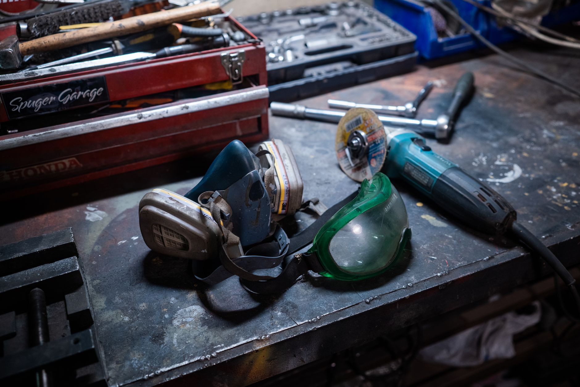 rows of military-issue gas masks and protective equipment laid out on a training table in a stark indoor facility