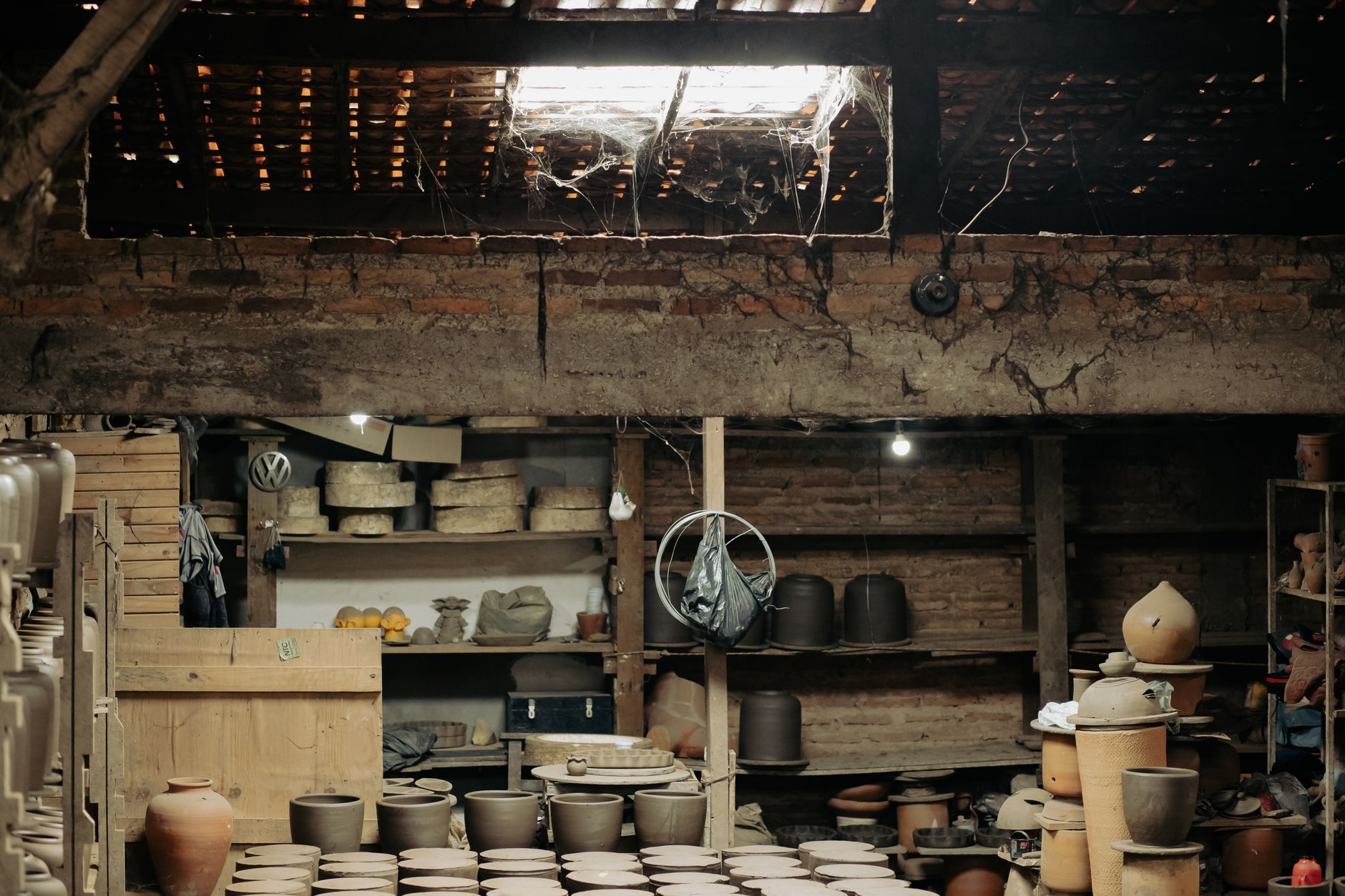 rows of small fixed-wing drone airframes in various stages of assembly inside a portable prefabricated shelter structure, tools and material spools visible on shelving units along the walls