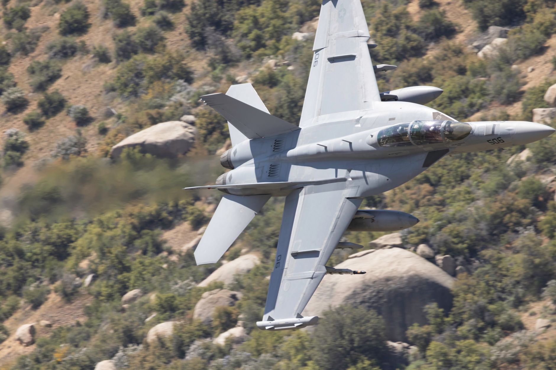 an F/A-18F Super Hornet aircraft parked on a flight line at an Australian air force base, viewed from a low angle showing the aircraft's fuselage and underwing hardpoints