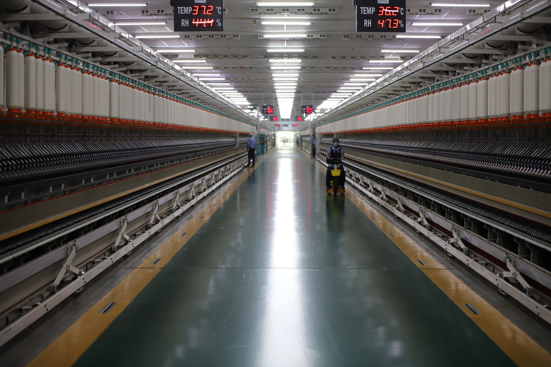 interior of a secure weapons production facility showing missile assembly stations with technicians working at a distance, emphasizing scale of the production floor