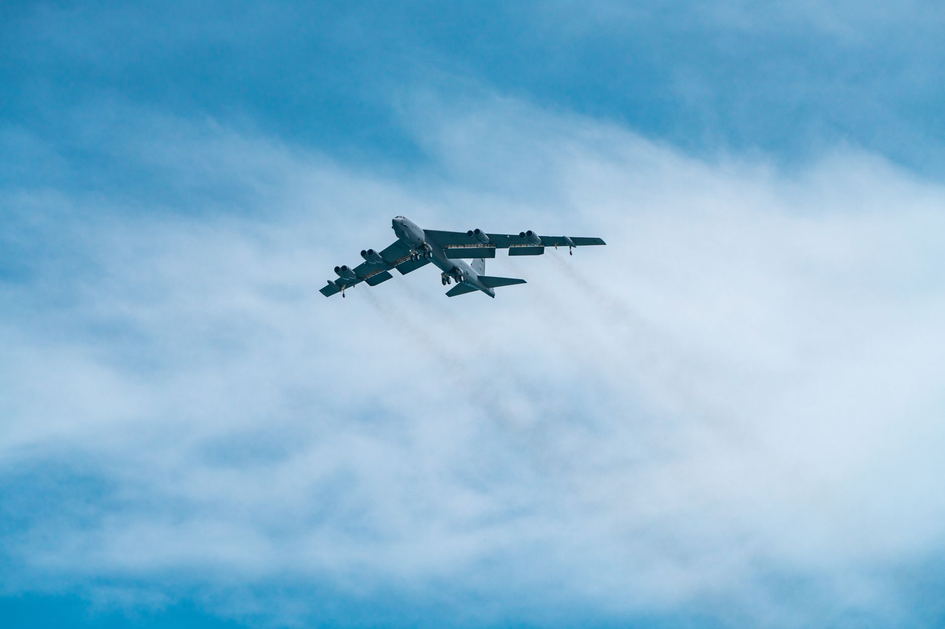 a B-52 Stratofortress heavy bomber parked on a flight line at a U.S. Air Force base, engines visible under the swept wings, maintenance equipment positioned nearby