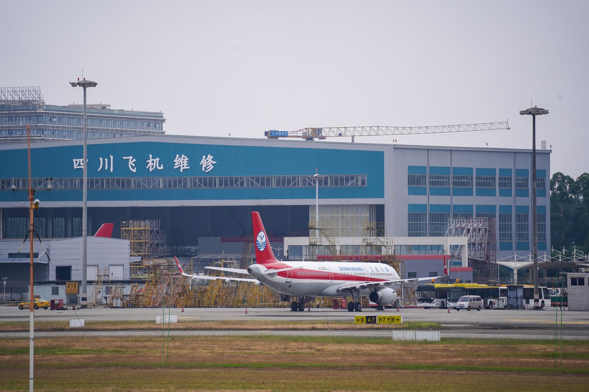 exterior of a large Chinese aviation manufacturing complex with enclosed hangars and taxiway infrastructure, no personnel visible as focal point