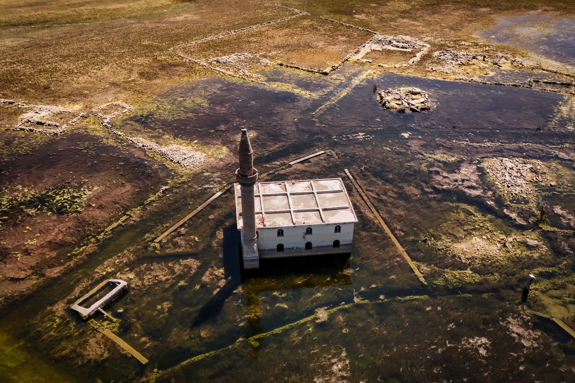 wide aerial satellite view of a remote desert military airbase complex with runways, taxiways, and construction equipment visible across a dry lakebed landscape