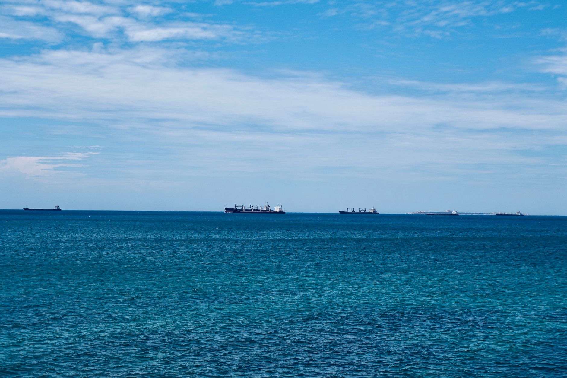 a naval carrier strike group at sea viewed from a wide overhead angle, ships in formation on open ocean