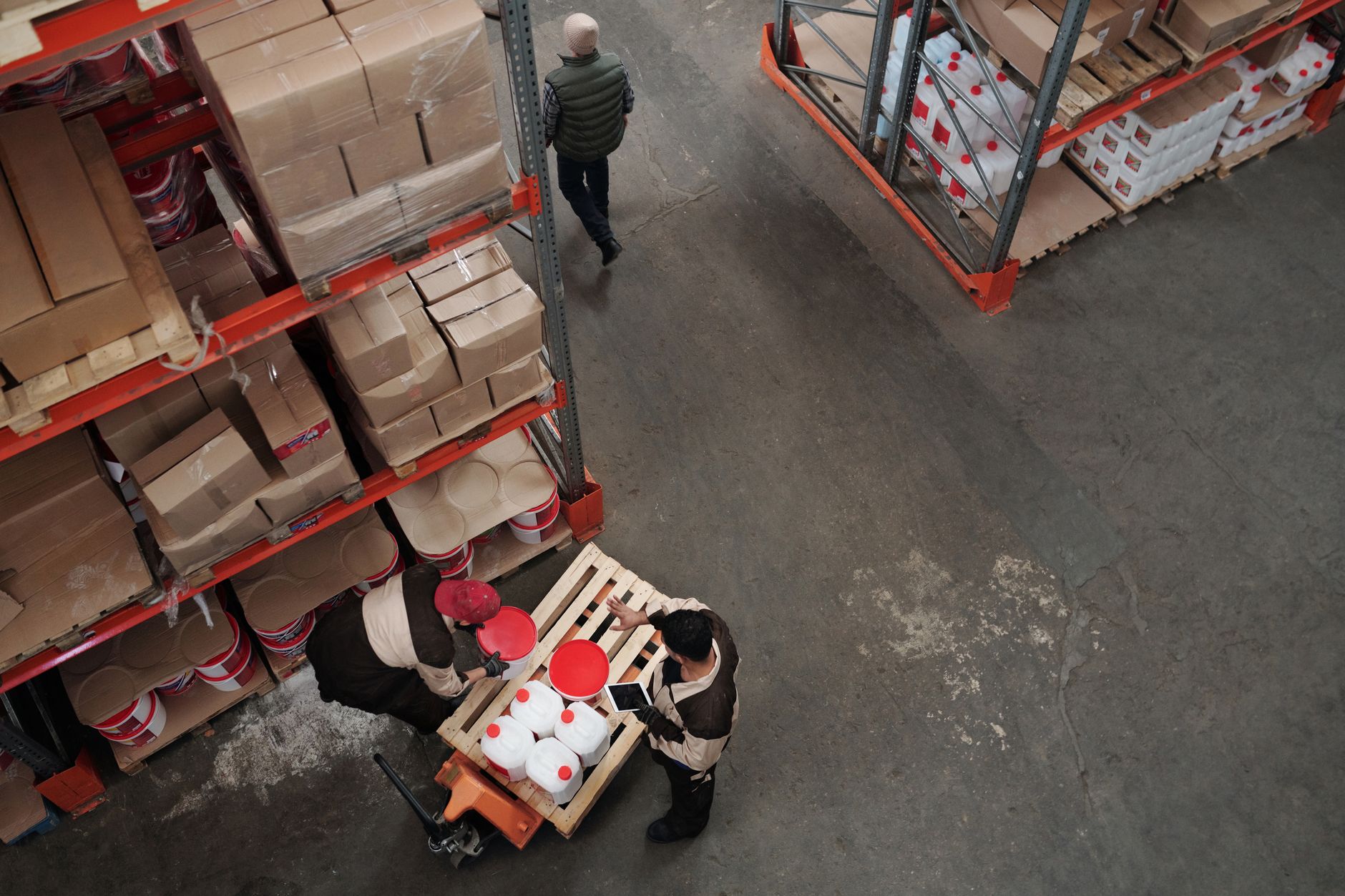 rows of small fixed-wing unmanned aerial vehicles on a warehouse storage floor, viewed from a wide angle showing scale of inventory