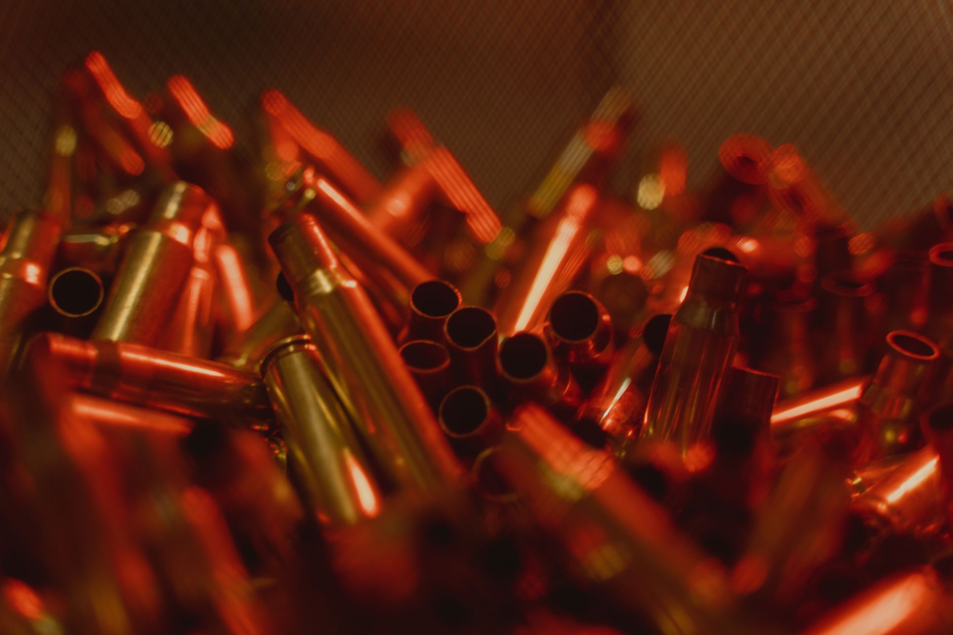 rows of large-caliber artillery shells arranged in a manufacturing facility, with industrial machinery and overhead lighting visible in the background