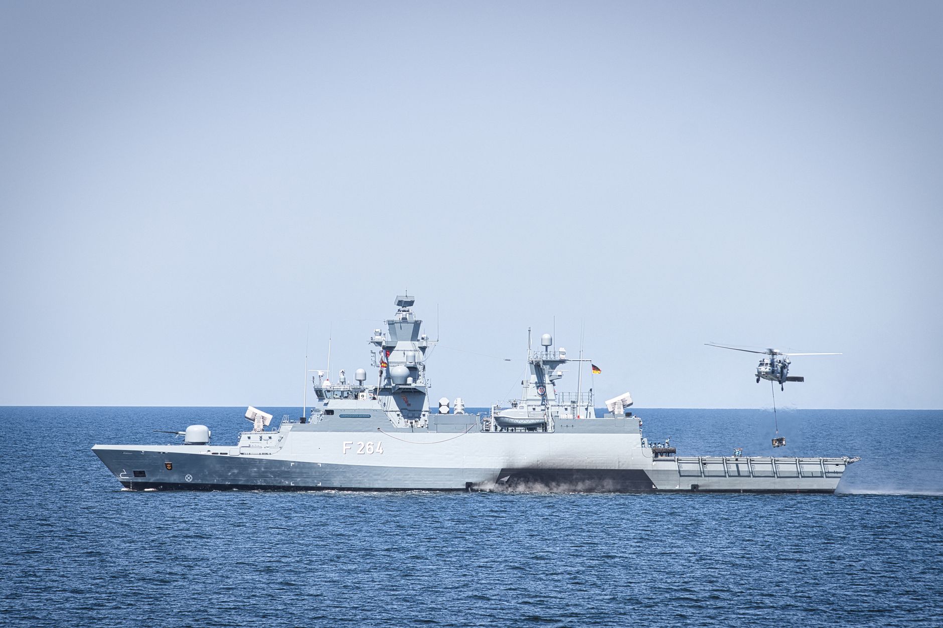 a European Union naval frigate underway in open blue water, viewed from an elevated angle, with no other vessels nearby