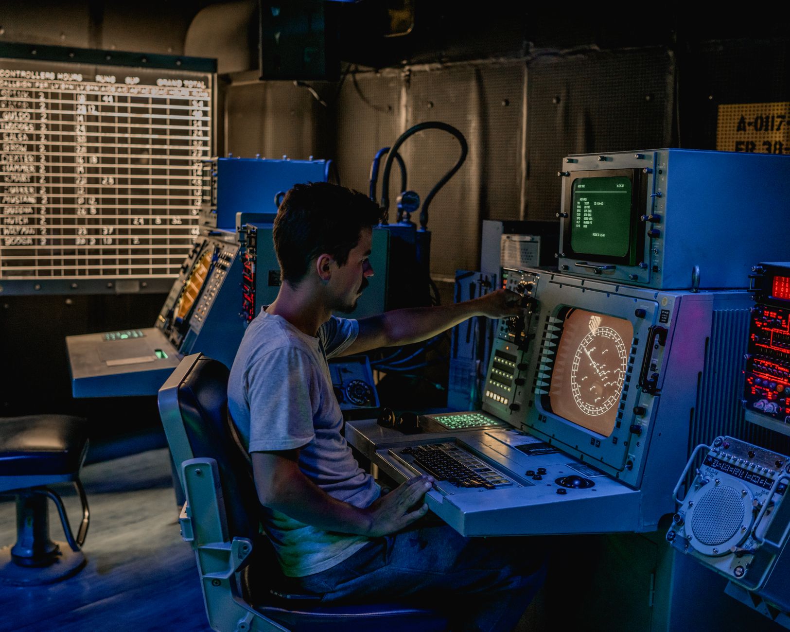 interior of a combined military operations center with large digital display screens showing the Korean Peninsula, consoles arranged in rows, and overhead lighting casting a blue tint across the room