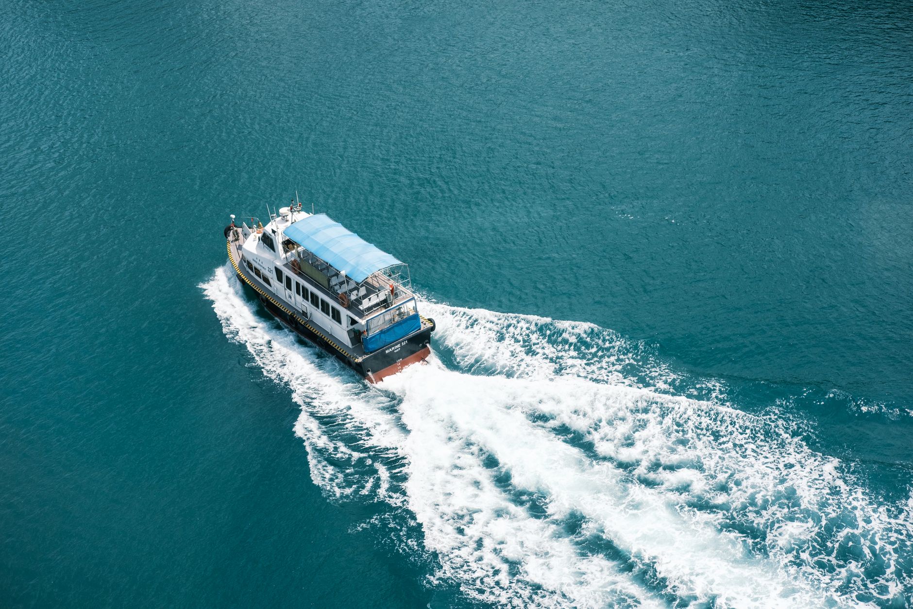 an unmanned surface vessel underway on open water during sea trials, viewed from an elevated angle with no crew visible on deck