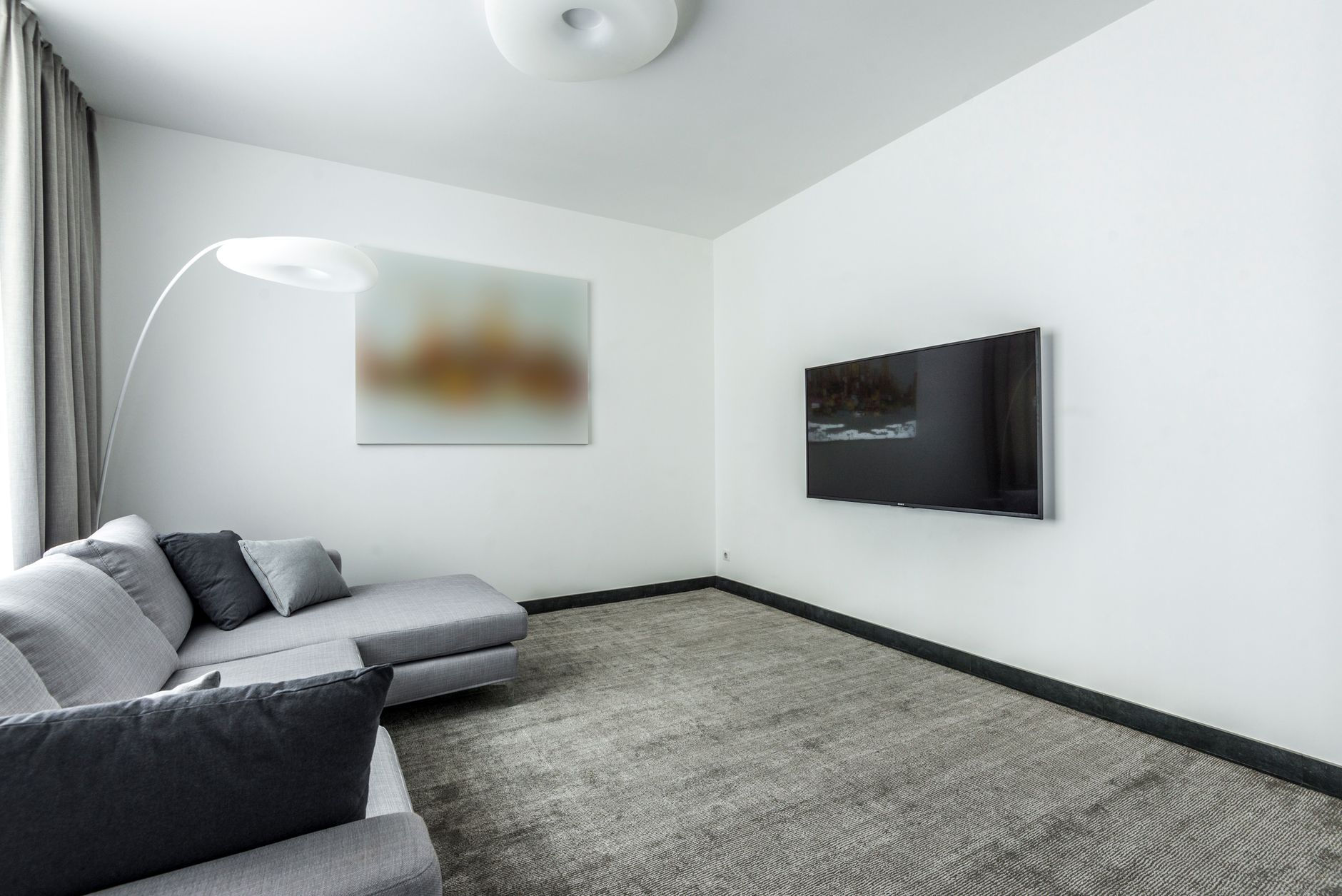 a large flat-screen television mounted in a modern living room displaying a fantasy medieval castle landscape, room softly lit in evening light