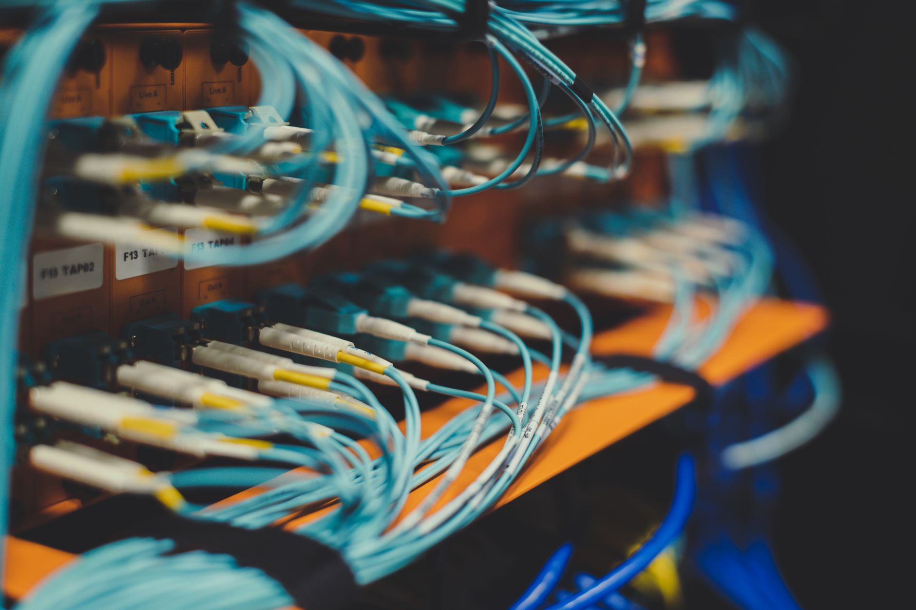 a large server infrastructure hall filled with rows of active computing racks, indicator lights blinking, cooling ducts running overhead, no people visible