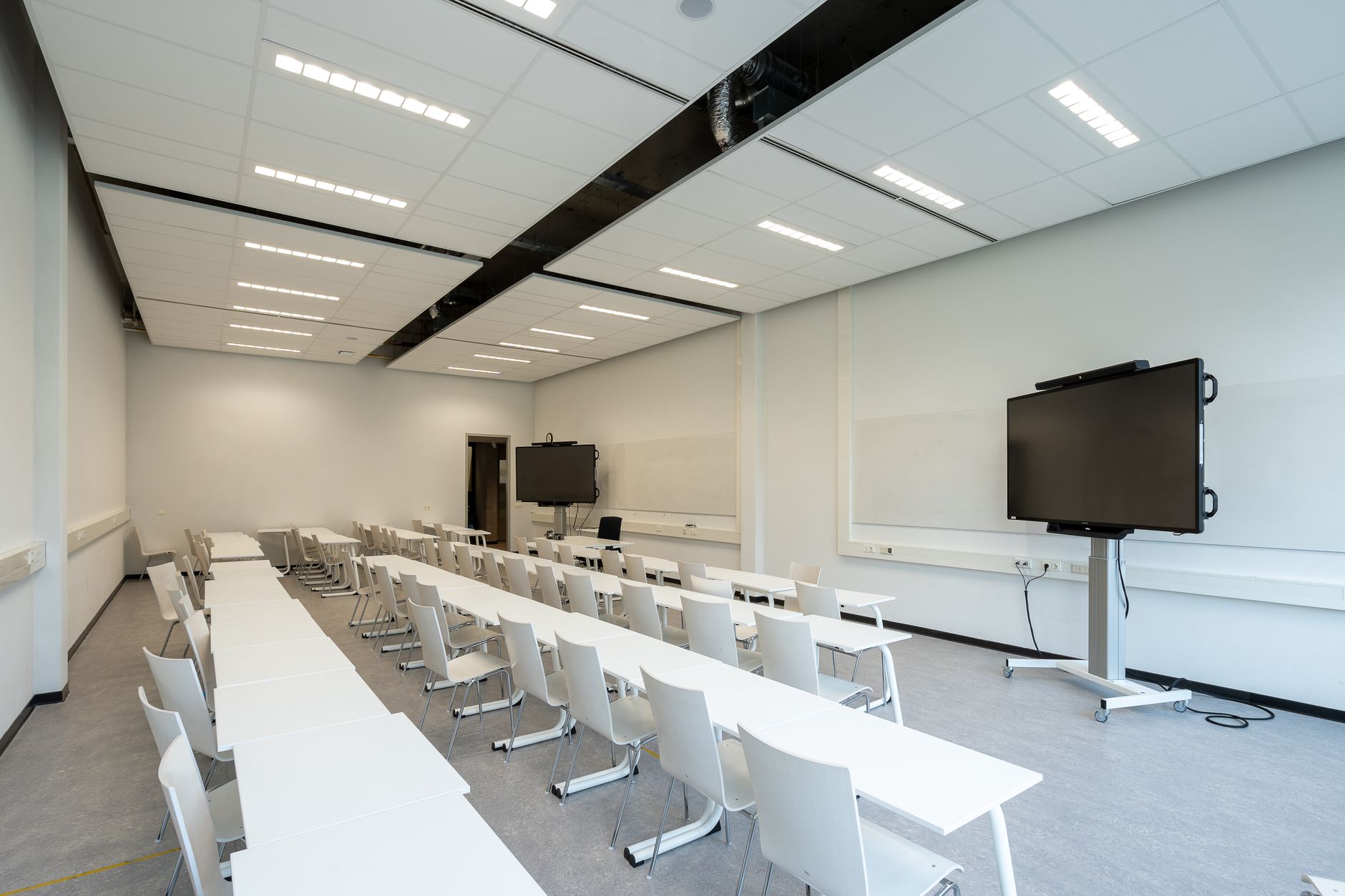 a technology policy conference room with large projection screens displaying AI benchmark charts, empty chairs arranged around a long table, windows overlooking an urban skyline