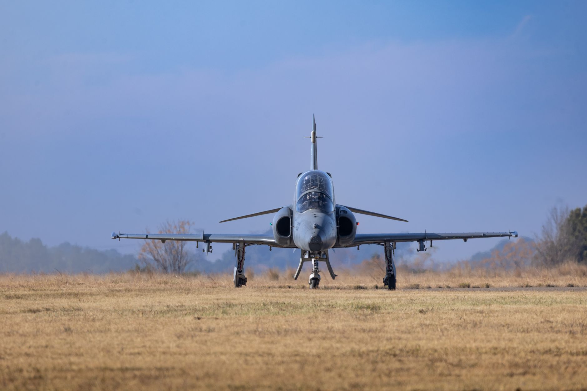 A sleek jet trainer aircraft parked on a tarmac at a Turkish aerospace manufacturing facility, viewed from a low angle with the aircraft's air intakes and swept wings as the focal point