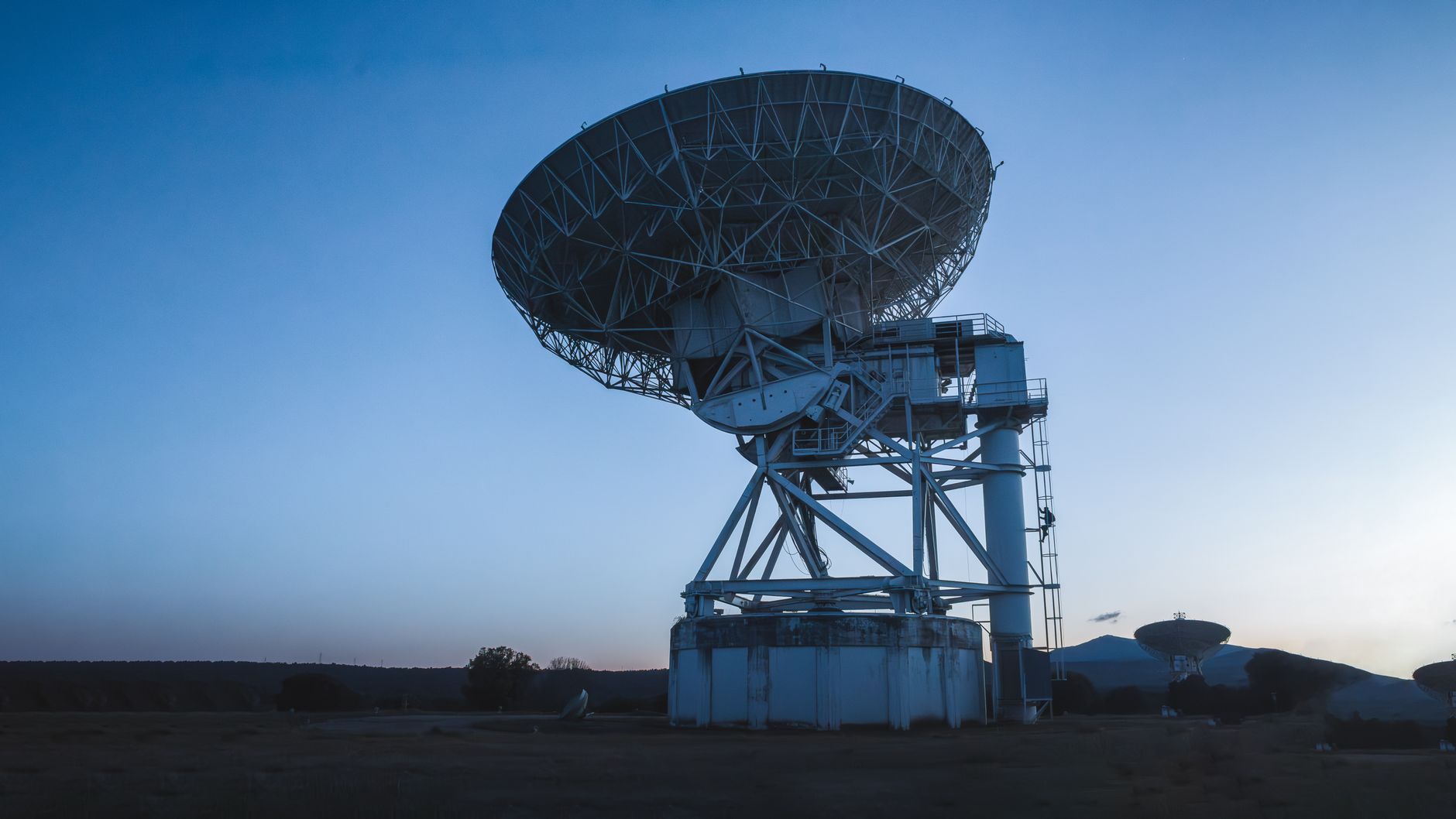 an aerial view of a satellite integration and testing facility exterior, with large antenna test ranges visible on the grounds