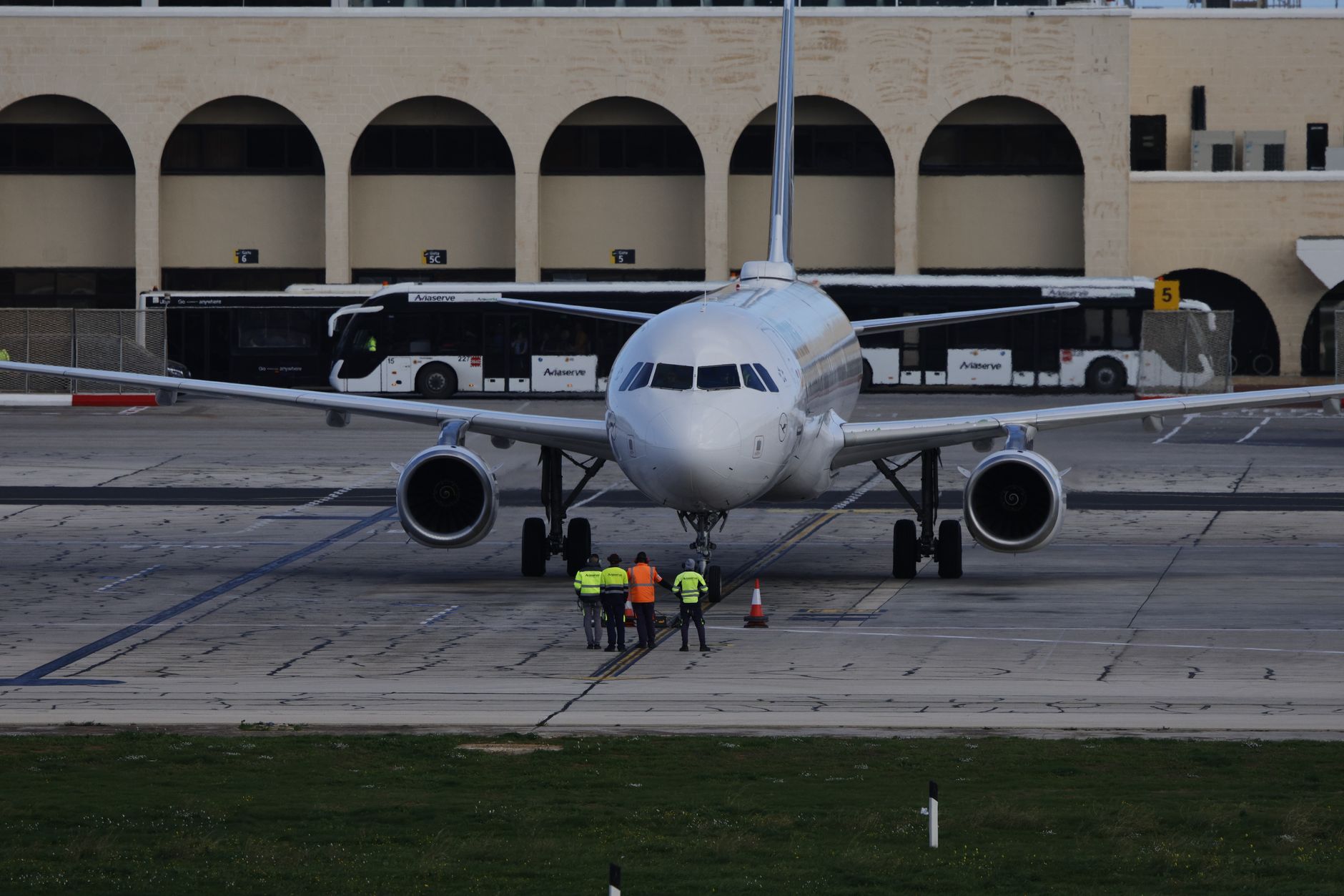 wide exterior shot of a large government aircraft parked on a tarmac at dusk, ground crew visible at a distance near the tail section