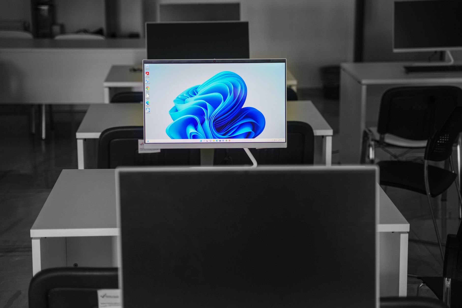 rows of desktop workstations inside a government cybersecurity operations center, monitors displaying network activity dashboards, no personnel visible