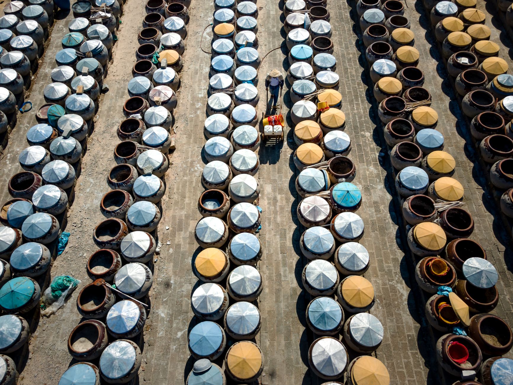 rows of Tamir interceptor missiles loaded in Iron Dome launch canisters inside a military logistics facility, canister caps visible, overhead industrial lighting