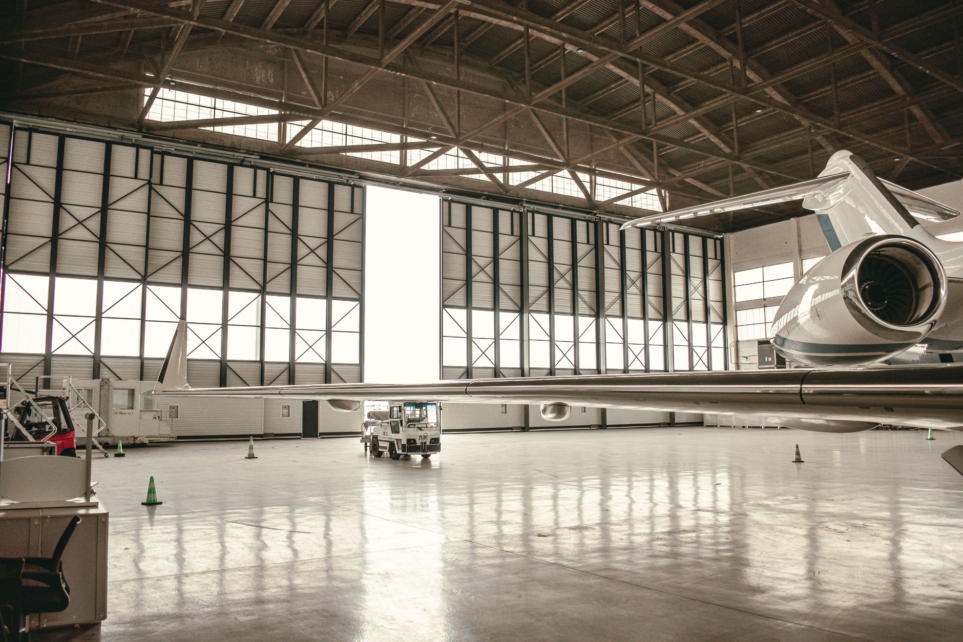 a disassembled F-15 airframe in a large military maintenance hangar, structural panels removed and laid out on the floor, overhead lighting illuminating the bare metal skeleton