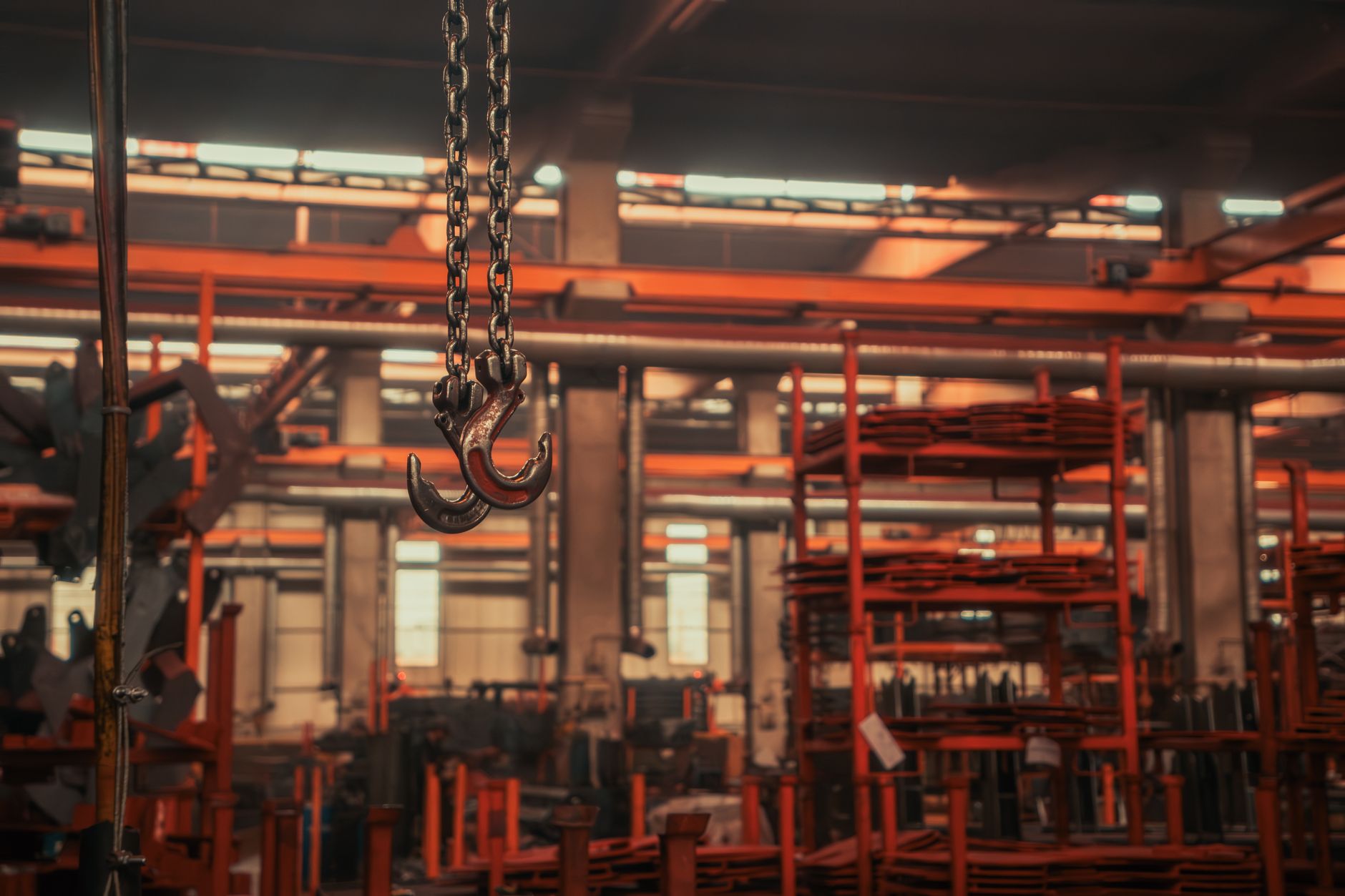 A large aerospace manufacturing hangar interior showing helicopter airframe components on assembly fixtures, with industrial lighting overhead and tooling carts positioned along the production line