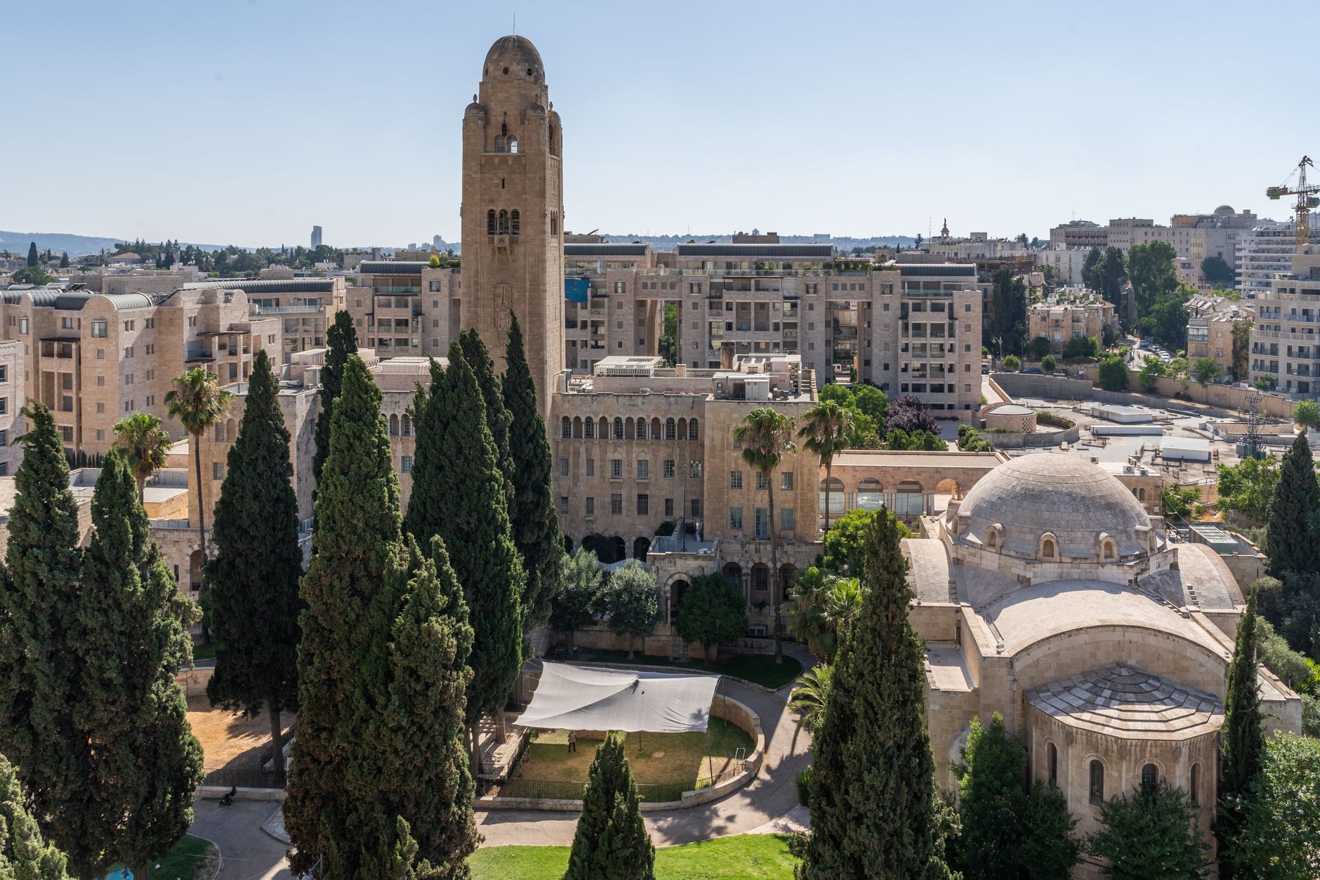 aerial view of a large government ministry complex in Jerusalem, with wide stone plazas and administrative buildings visible in late-afternoon light